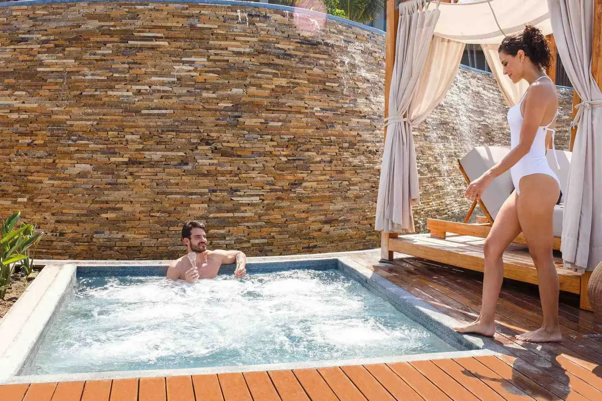 Couple relaxing by a spa whirlpool and cabana at Armony Marival, Puerto Vallarta