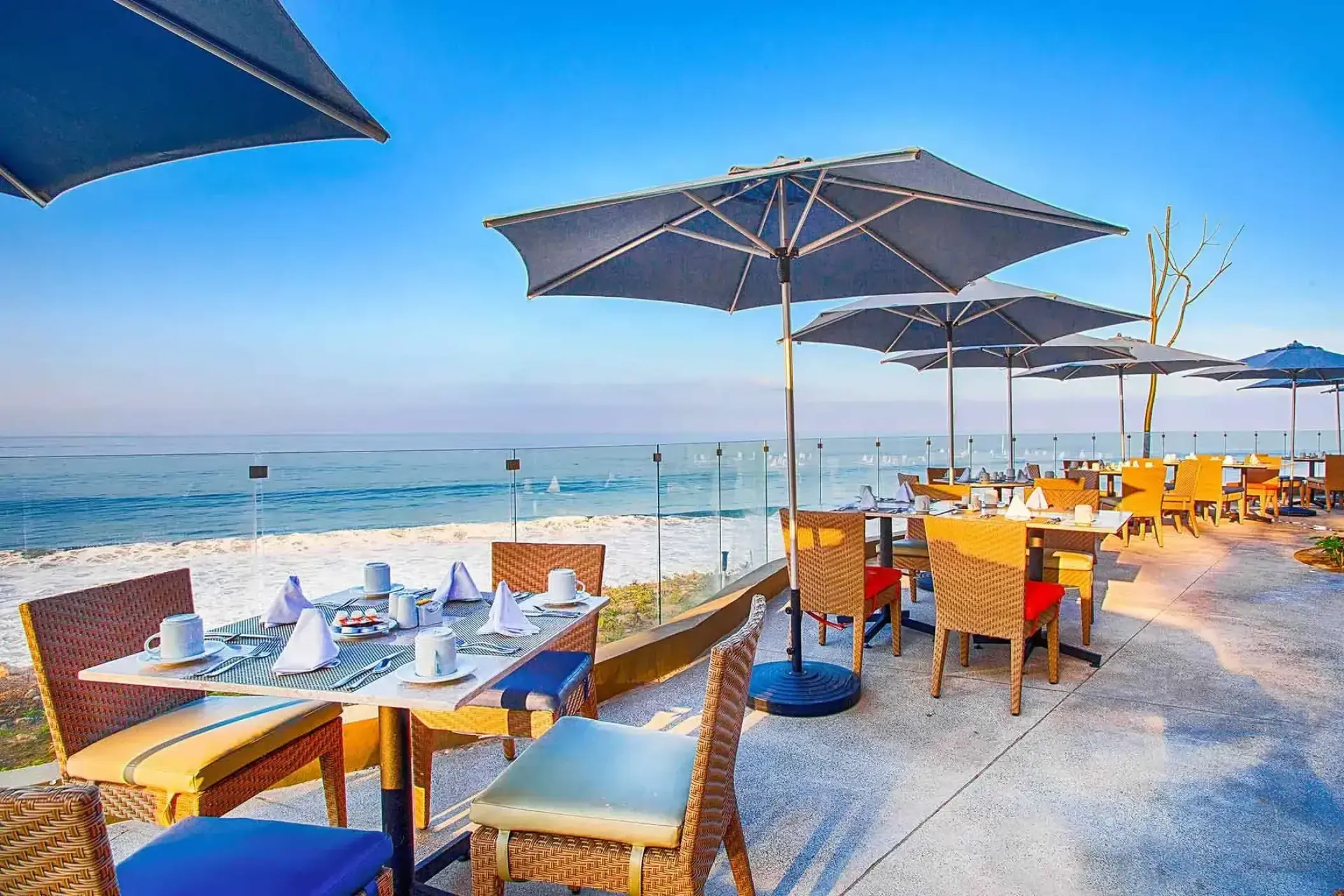 Outdoor dining tables with umbrellas overlooking the ocean at Armony Marival, Puerto Vallarta