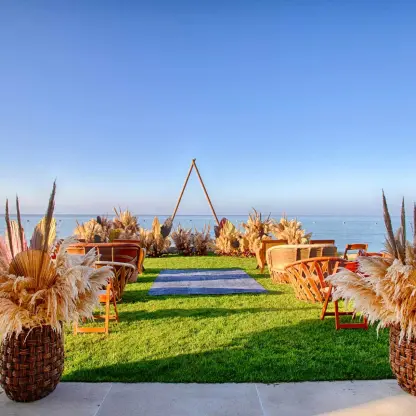 Beachfront wedding ceremony on a lawn with pampas grass and triangular arch at Armony Marival, Puerto Vallarta