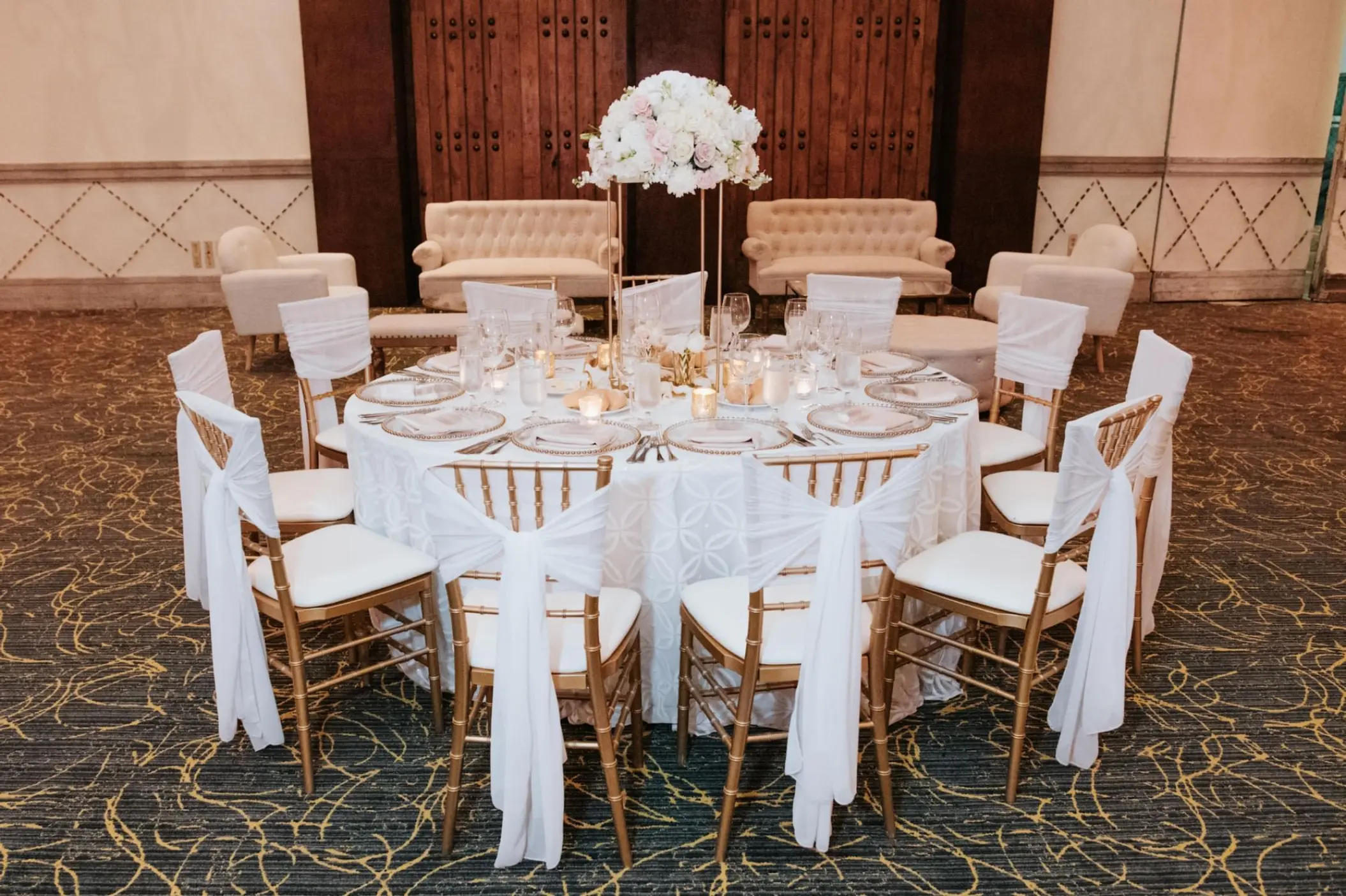 Indoor wedding reception table with white floral centerpiece and gold chairs at Marquis Los Cabos, Cabo San Lucas