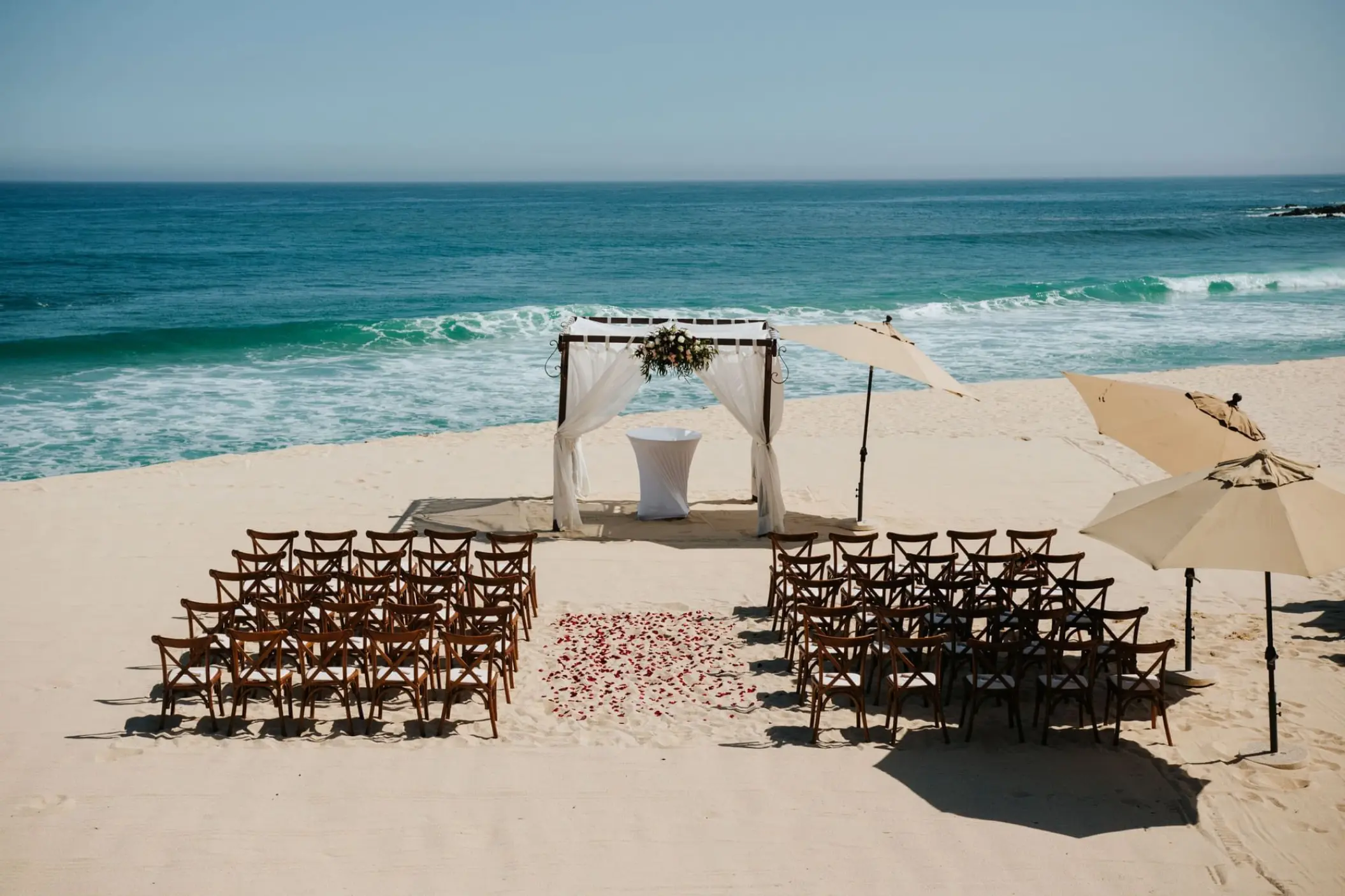 Beachfront wedding ceremony with a white fabric arch at Marquis Los Cabos, Cabo San Lucas
