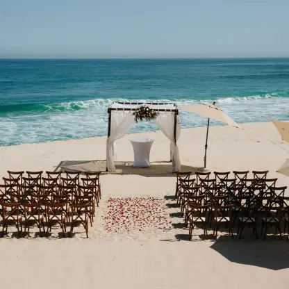 Beachfront wedding ceremony with a white fabric arch at Marquis Los Cabos, Cabo San Lucas