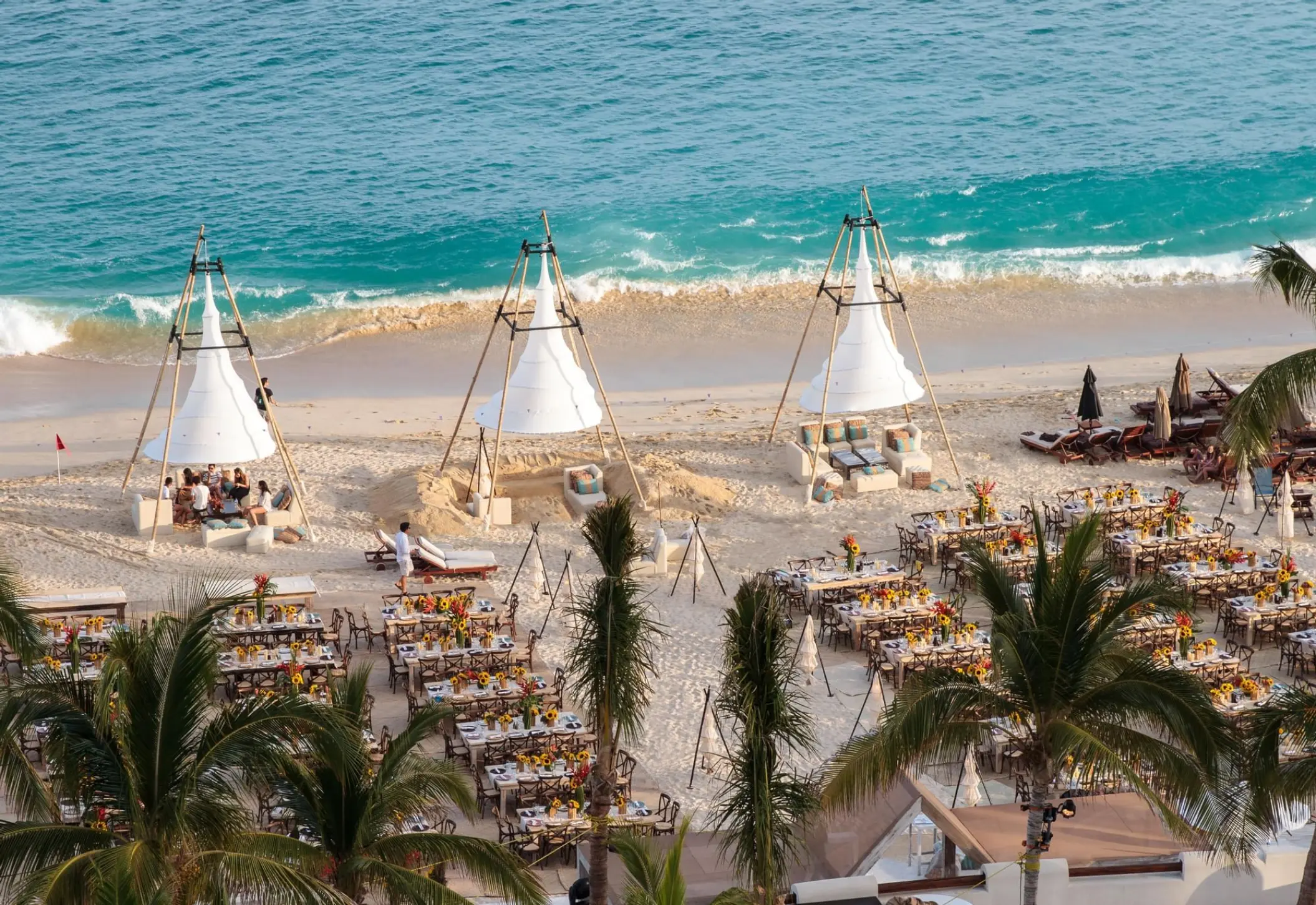 Beachfront wedding reception setup with white teepee structures and dinner tables at Marquis Los Cabos, Cabo San Lucas