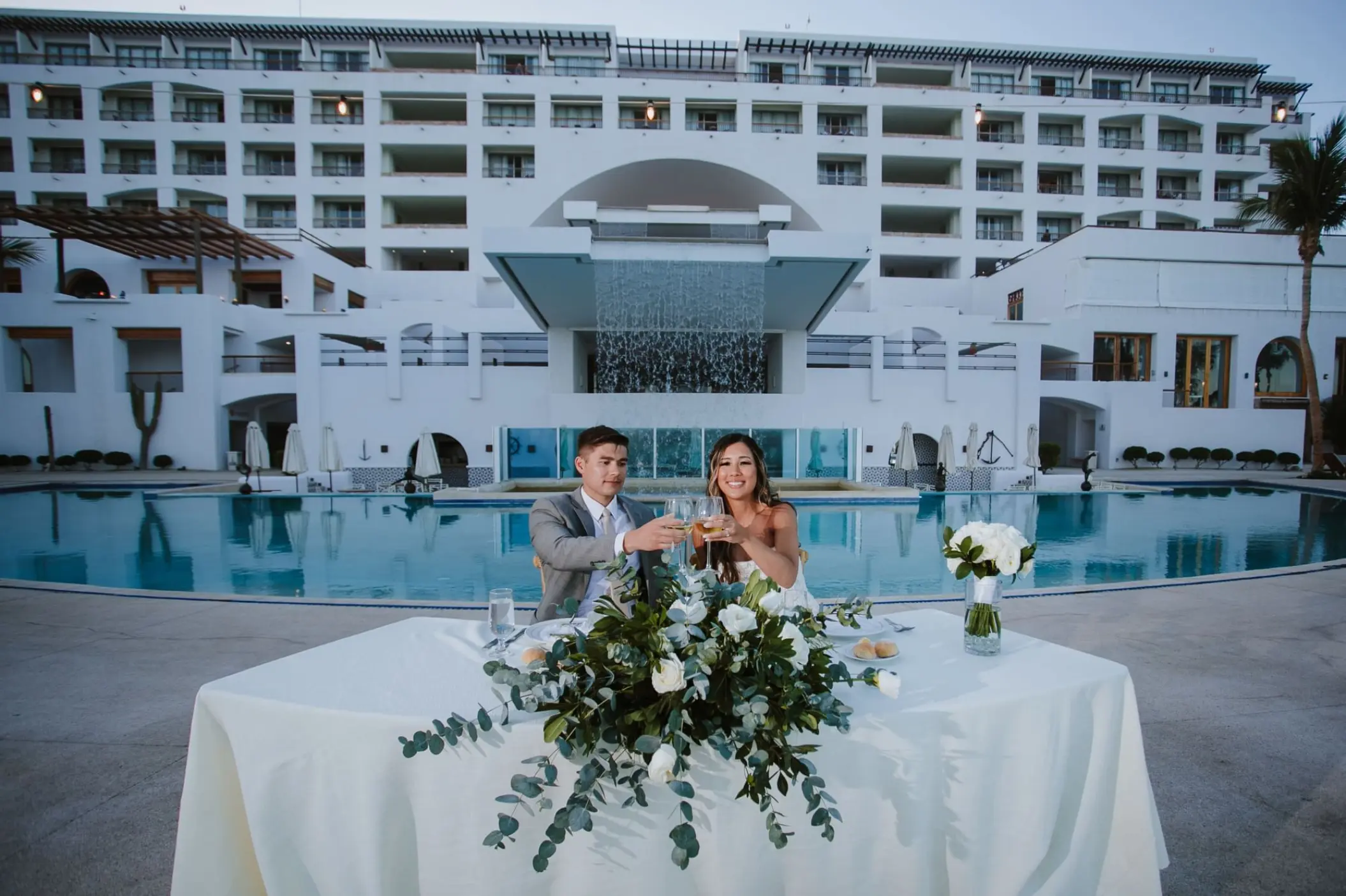 Bride and groom toasting at a pool terrace wedding reception at Marquis Los Cabos, Cabo San Lucas