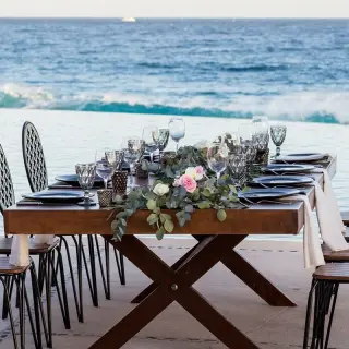 Wedding reception table with floral runner set beside an infinity pool at Marquis Los Cabos, Cabo San Lucas