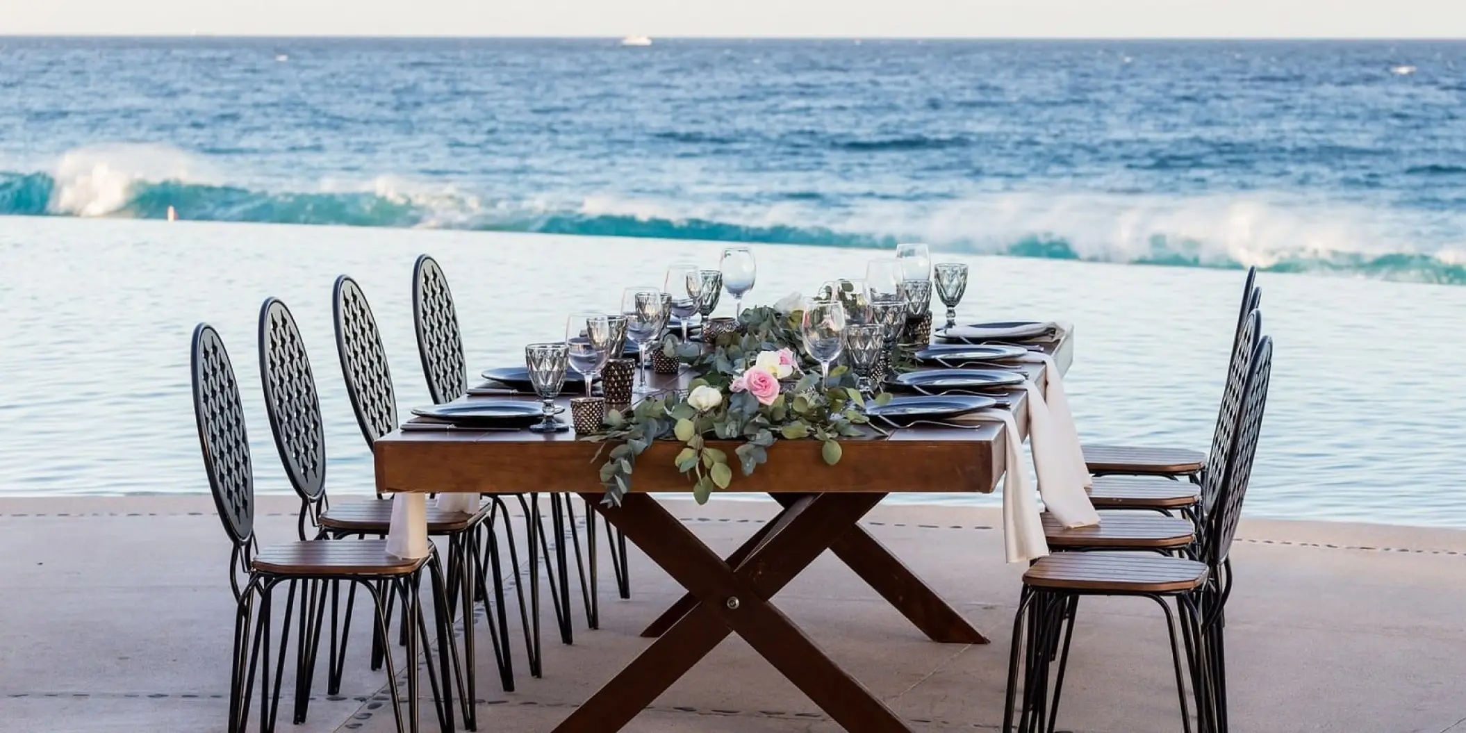 Wedding reception table with floral runner set beside an infinity pool at Marquis Los Cabos, Cabo San Lucas