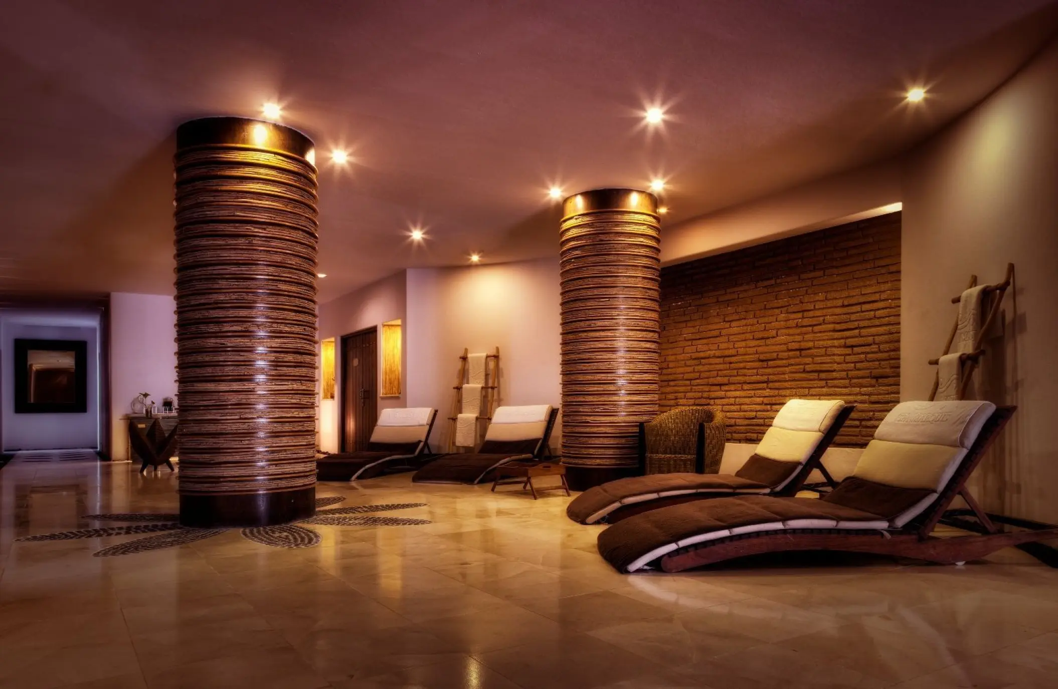 Indoor spa relaxation room with curved lounge chairs and decorative stone pillars at Marquis Los Cabos, Cabo San Lucas