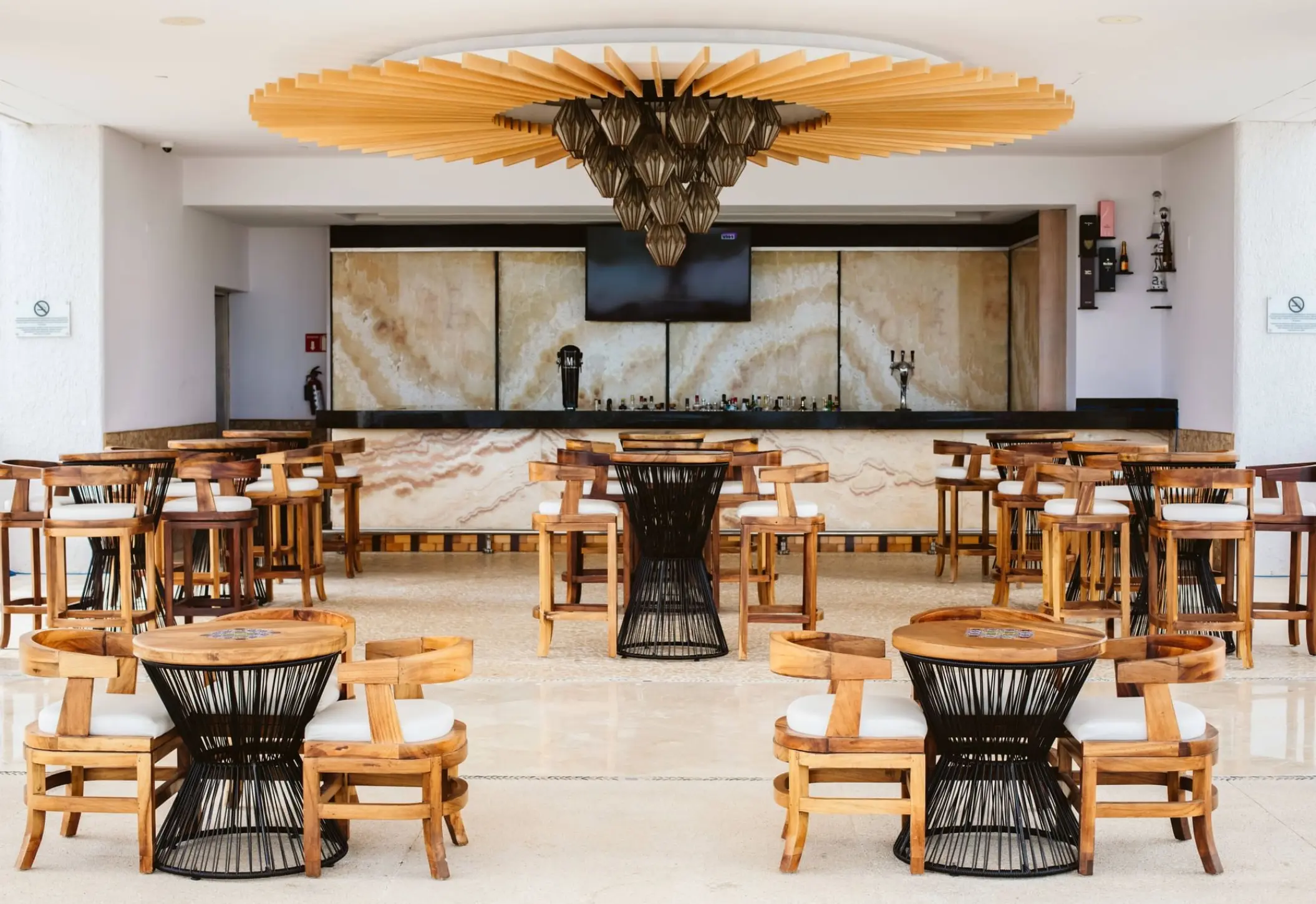 Suspiros Bar lounge with marble counters and ornate wood seating at Marquis Los Cabos, Cabo San Lucas