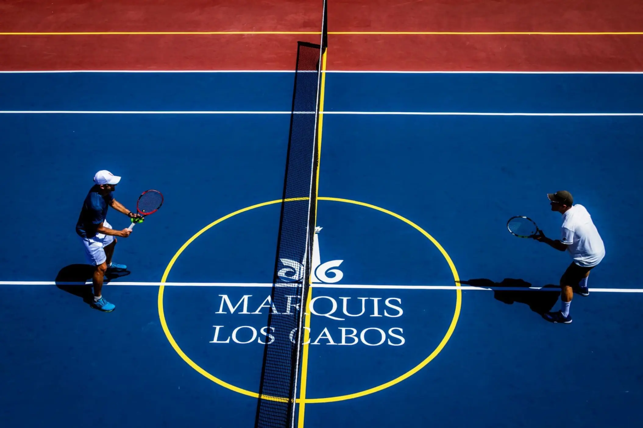 Overhead view of two people playing tennis on the blue courts at Marquis Los Cabos, Cabo San Lucas