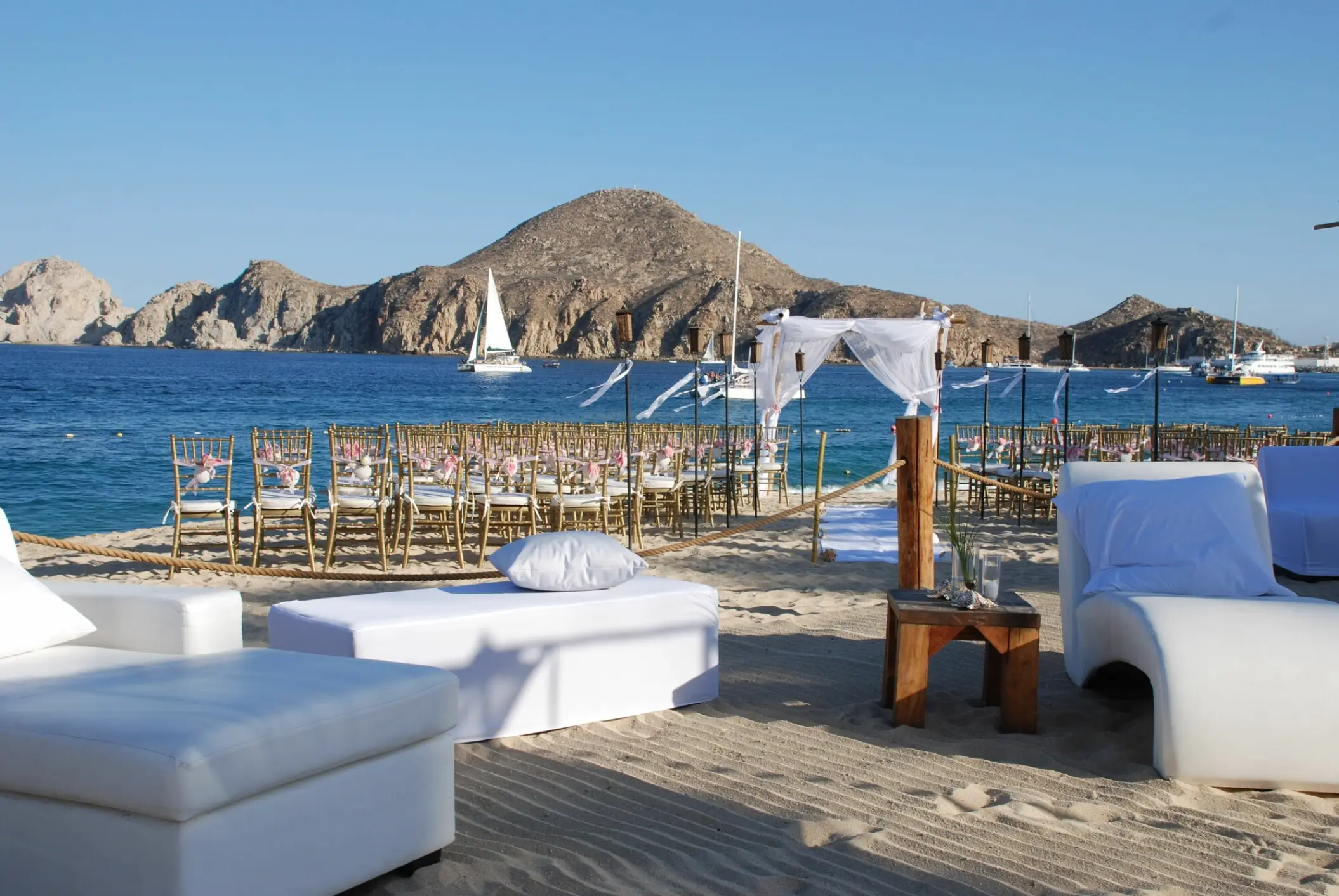 Beachfront wedding ceremony with white lounge seating at ME Cabo, Cabo San Lucas