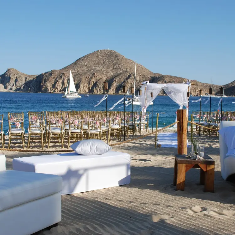 Beachfront wedding ceremony with white lounge seating at ME Cabo, Cabo San Lucas