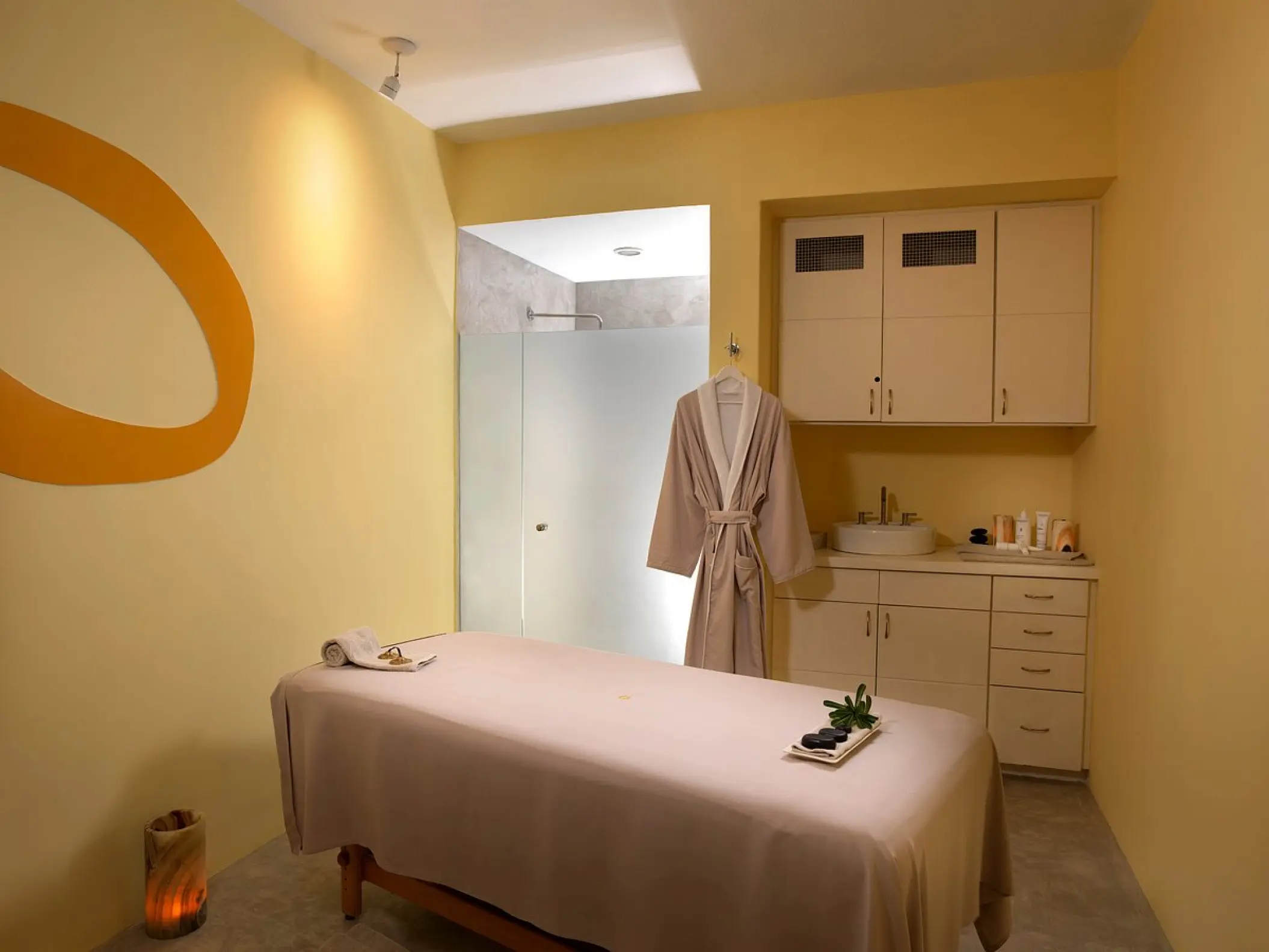 Spa massage room with treatment table and robe at ME Cabo, Cabo San Lucas