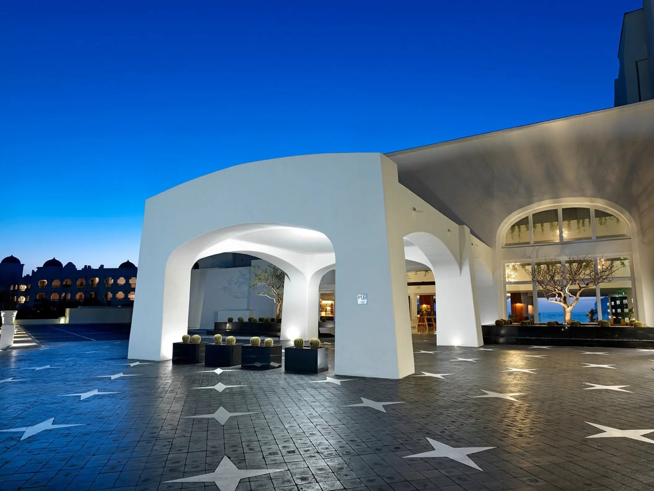 White arched entrance and star-patterned courtyard at ME Cabo, Cabo San Lucas