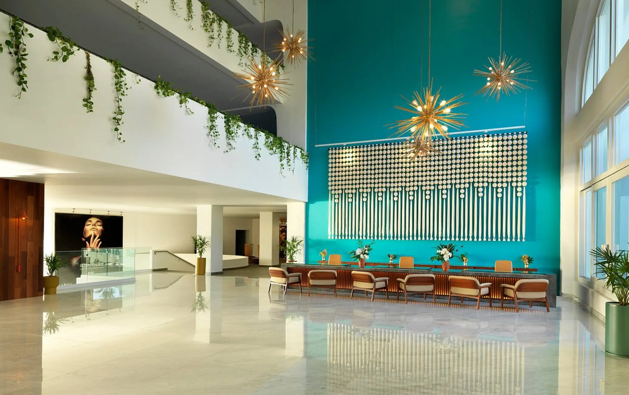 Modern lobby with turquoise feature wall and starburst chandeliers at ME Cabo, Cabo San Lucas
