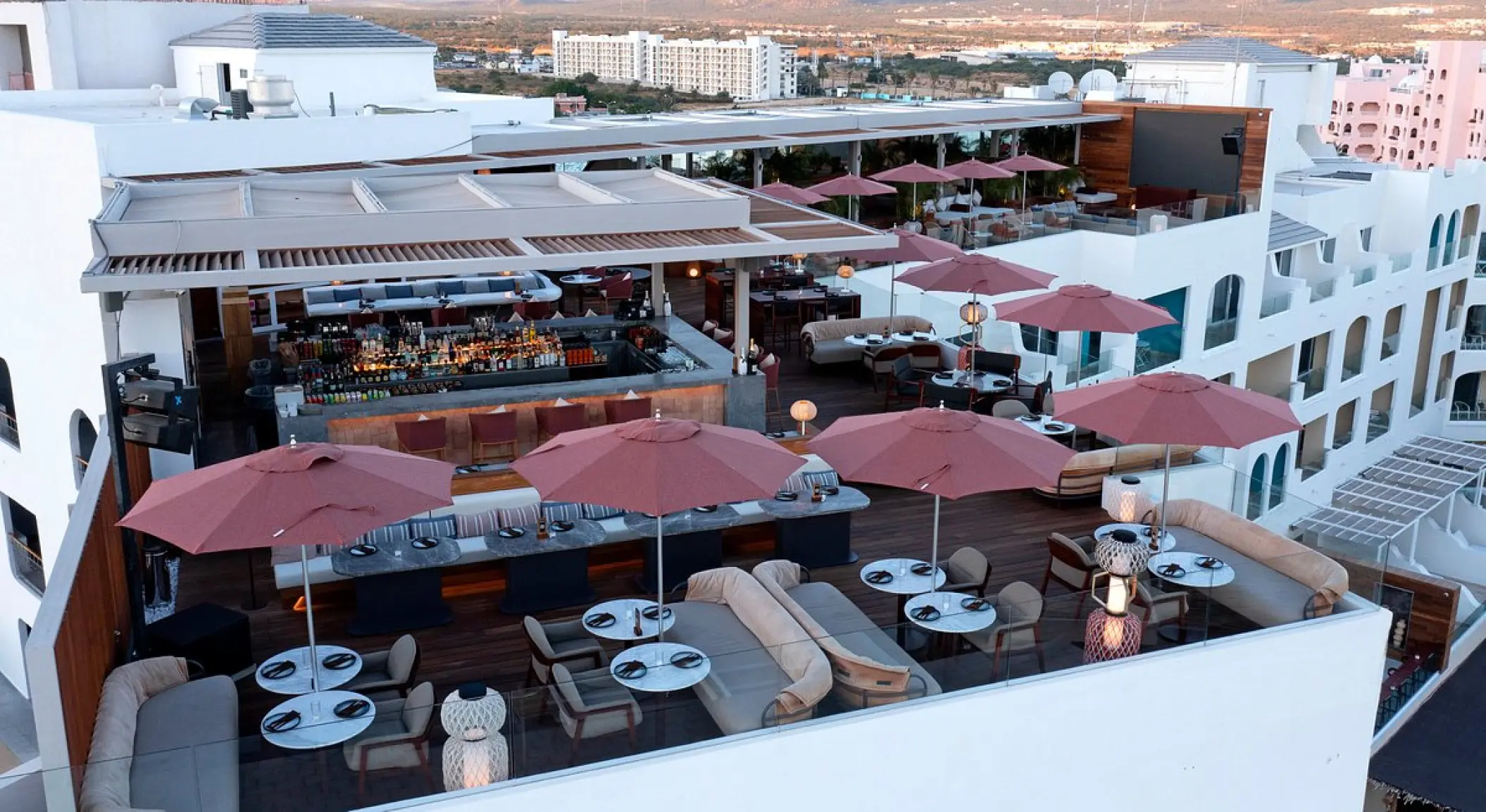 Vista del Confessions rooftop bar and lounge with red umbrellas at ME Cabo, Cabo San Lucas