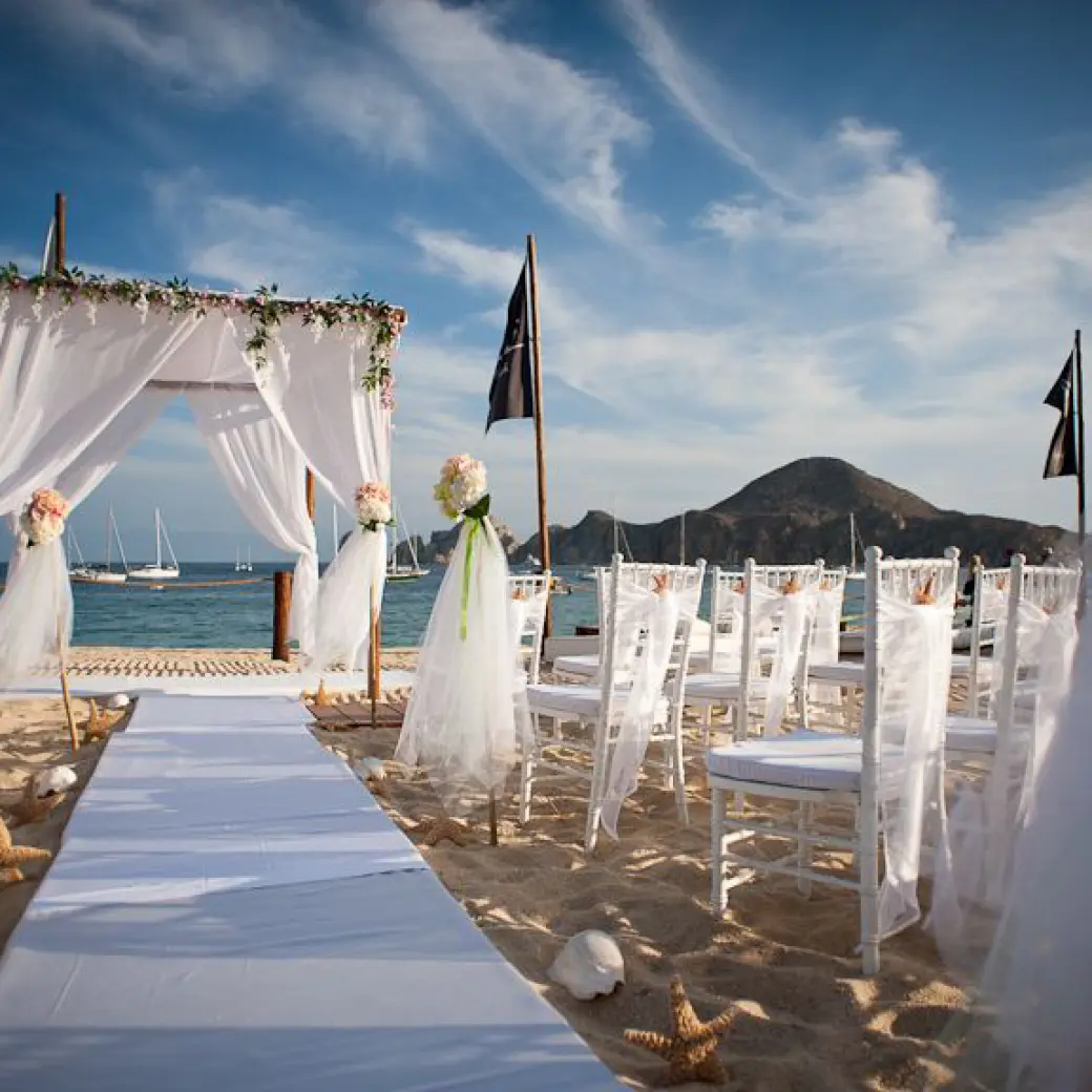 Beachfront wedding ceremony with white huppah and chairs at ME Cabo, Cabo San Lucas