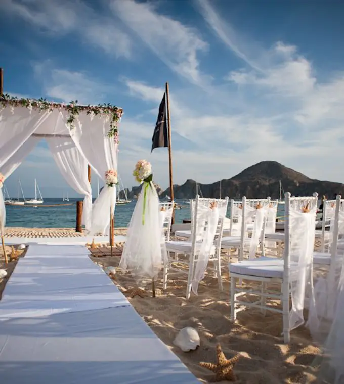 Beachfront wedding ceremony with white huppah and chairs at ME Cabo, Cabo San Lucas