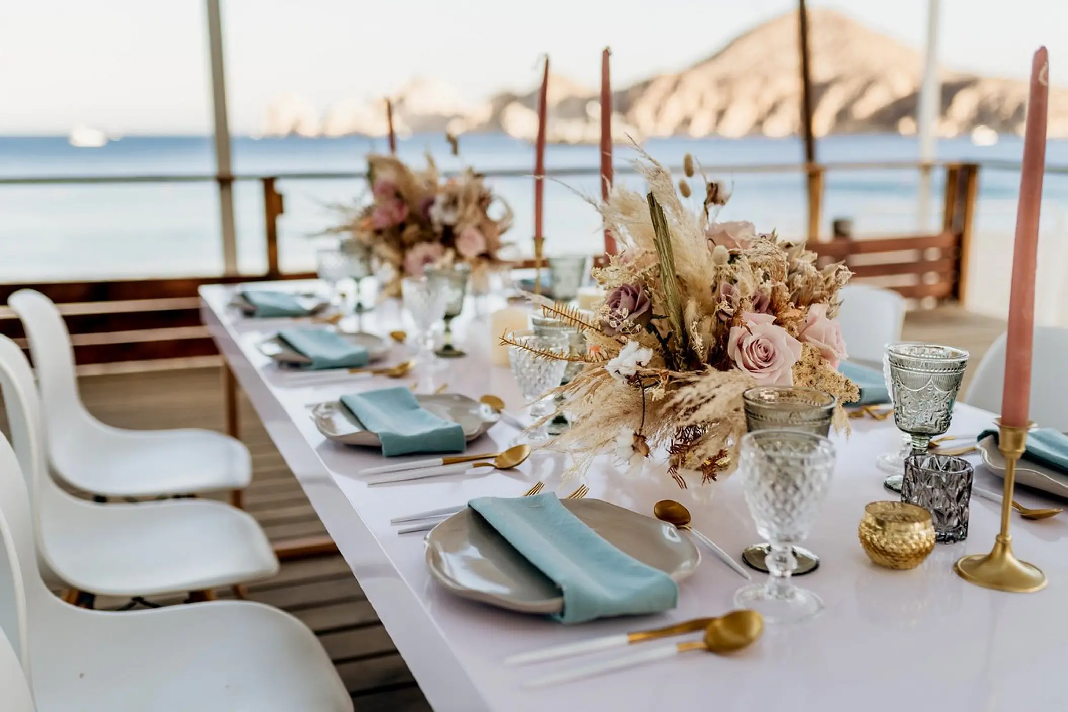 Terrace wedding reception at ME Cabo with floral centerpieces and ocean views, Cabo San Lucas