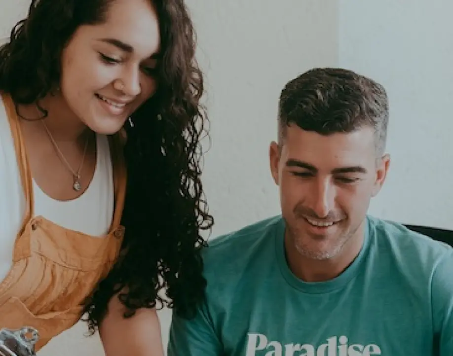 Two Paradise Weddings planners smiling and reviewing a clipboard together