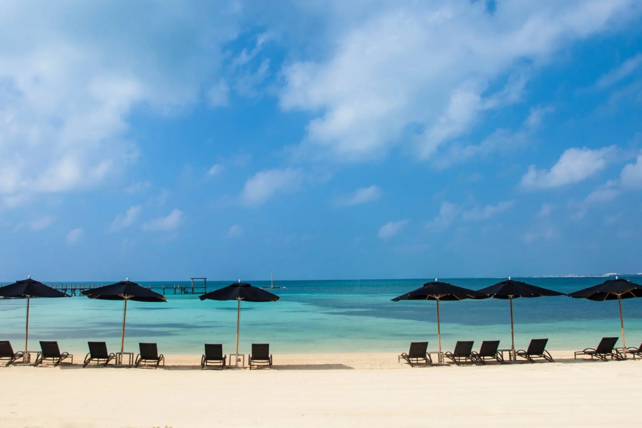 Black beach umbrellas and lounge chairs on the white sand at Nizuc Resort, Cancun