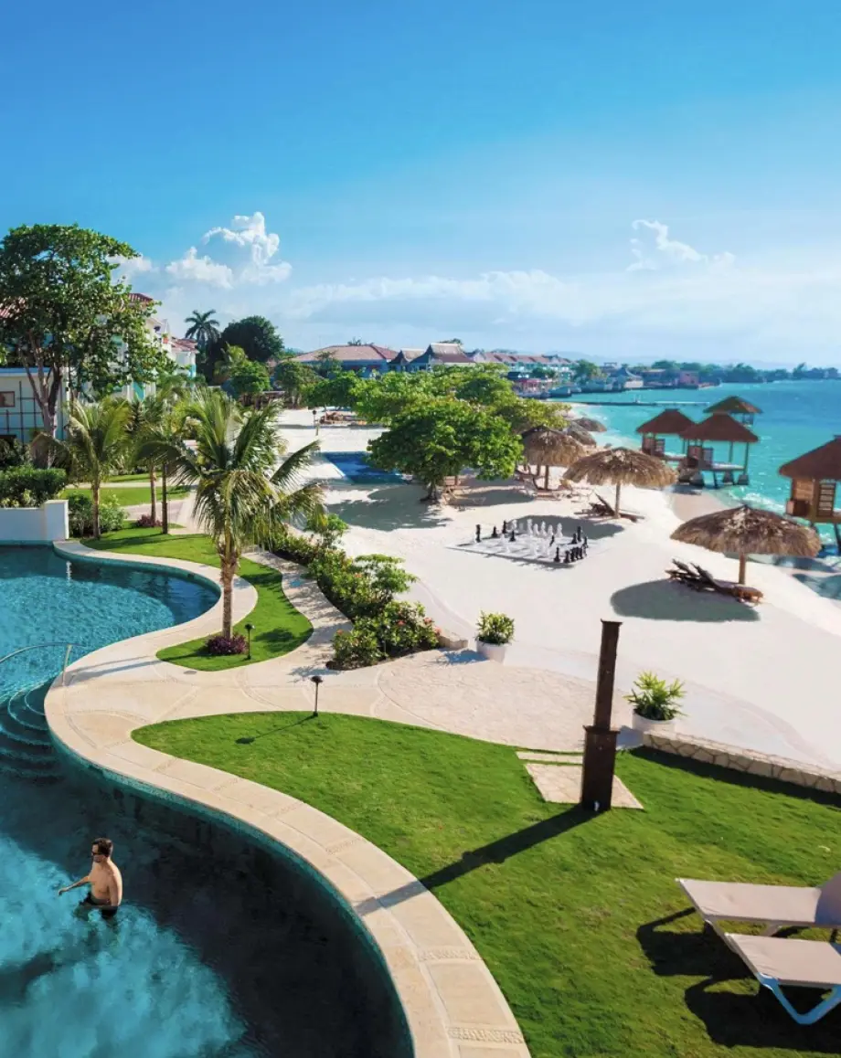 Aerial view of a beachfront swimming pool and sandy lounge area in Montego Bay