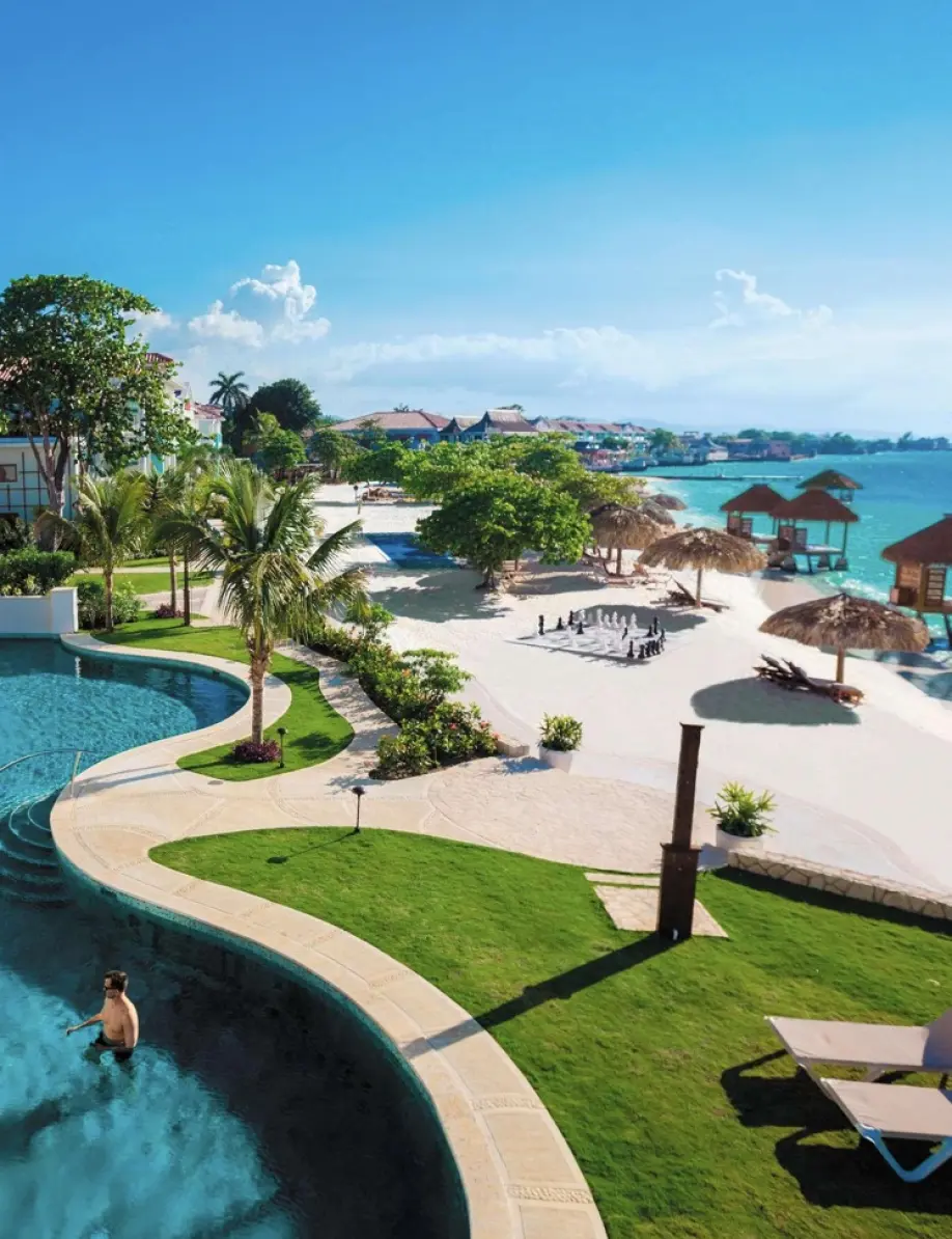 Aerial view of a beachfront swimming pool and sandy lounge area in Montego Bay