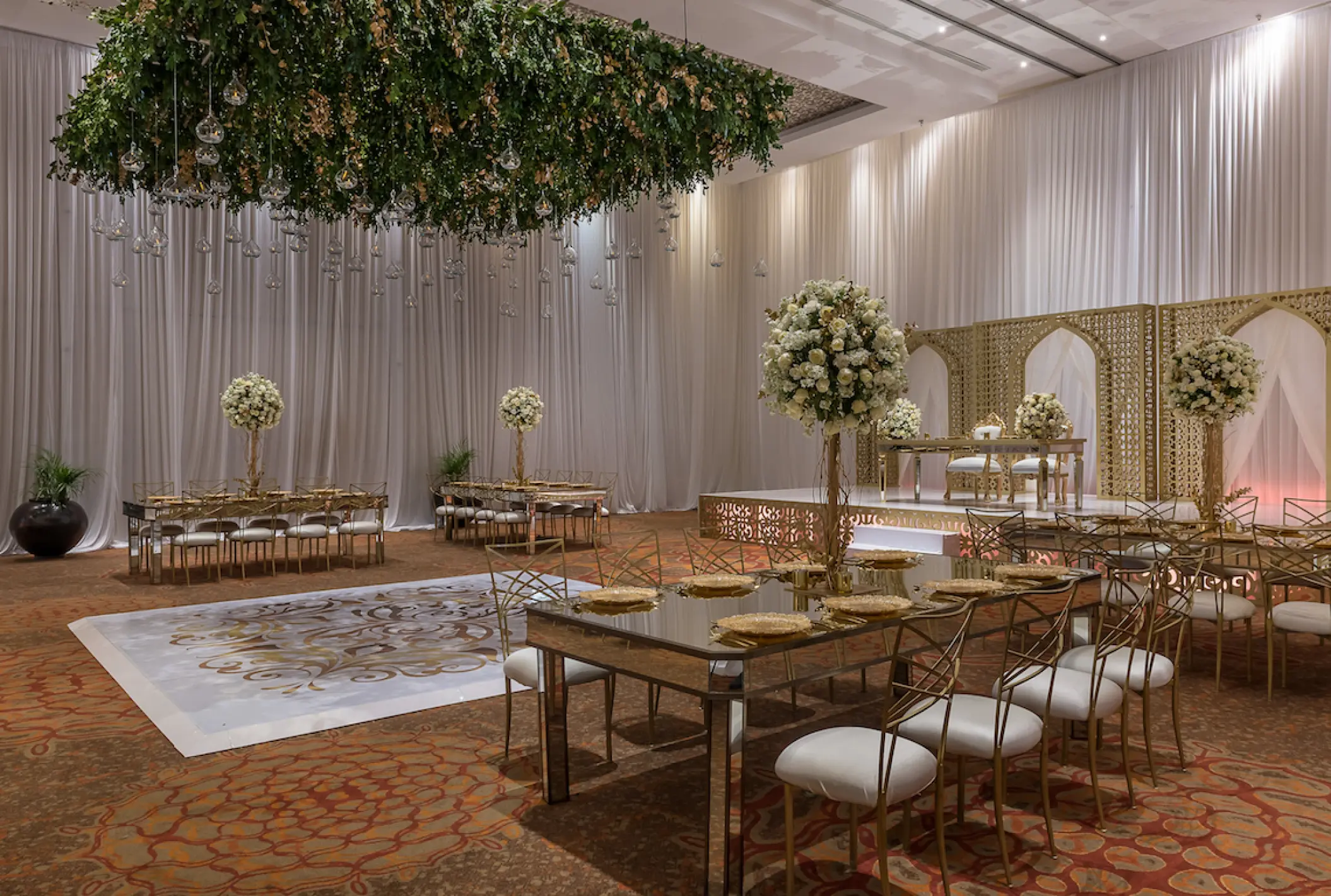Indoor ballroom wedding reception at Moon Palace Cancun with white floral centerpieces and gold chairs