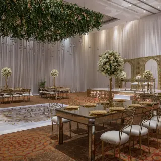 Indoor ballroom wedding reception at Moon Palace Cancun with white floral centerpieces and gold chairs