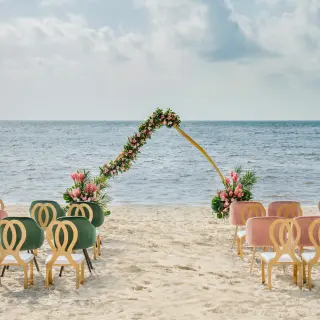 Beachfront wedding ceremony with a floral arch and velvet chairs at Moon Palace Cancun