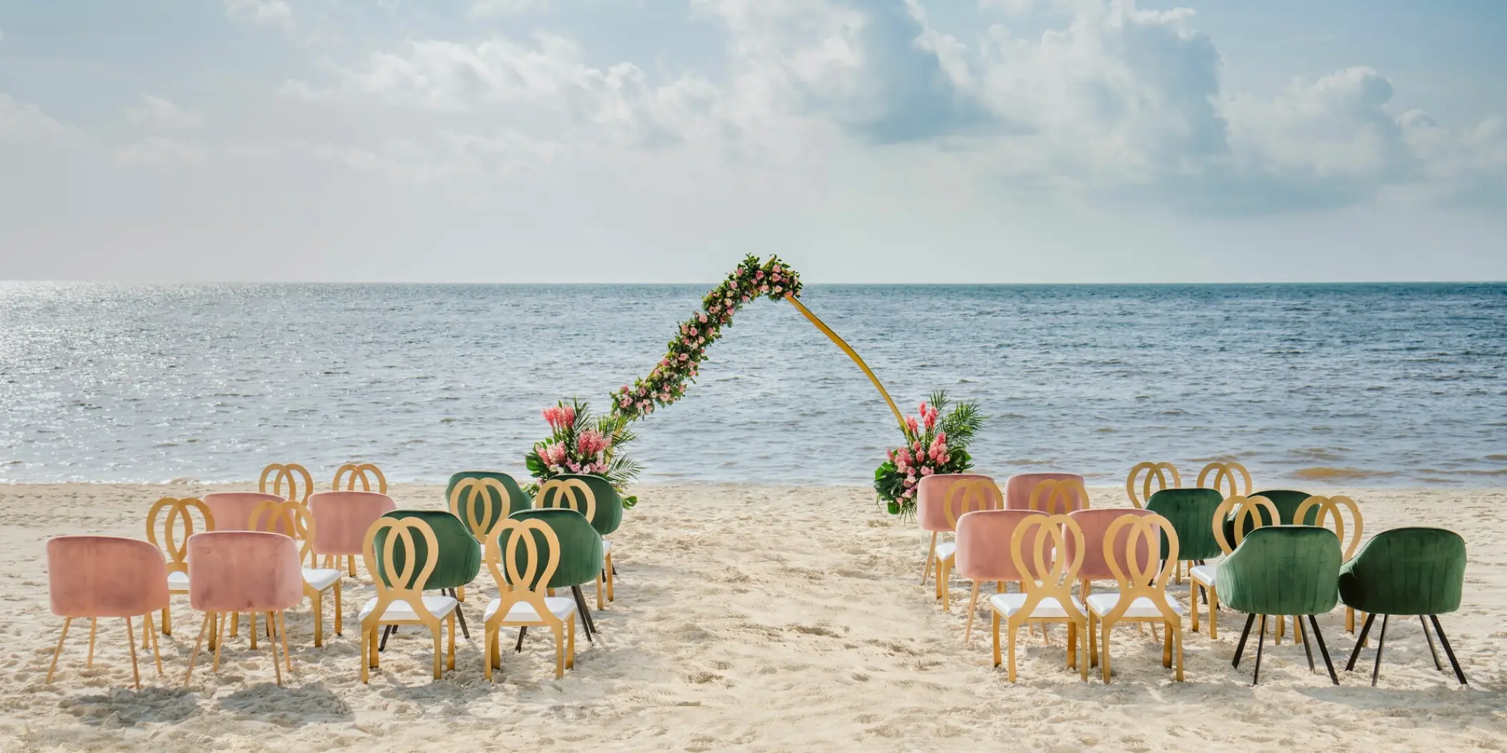 Beachfront wedding ceremony with velvet chairs and a floral arch at Moon Palace Cancun