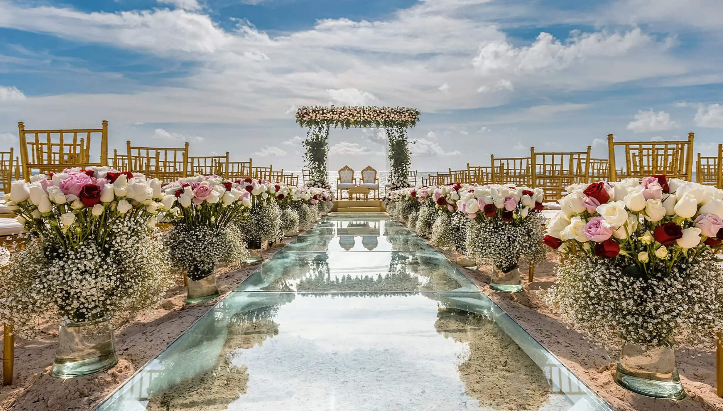 Glass aisle and floral arrangements for a beach ceremony at Moon Palace Cancun