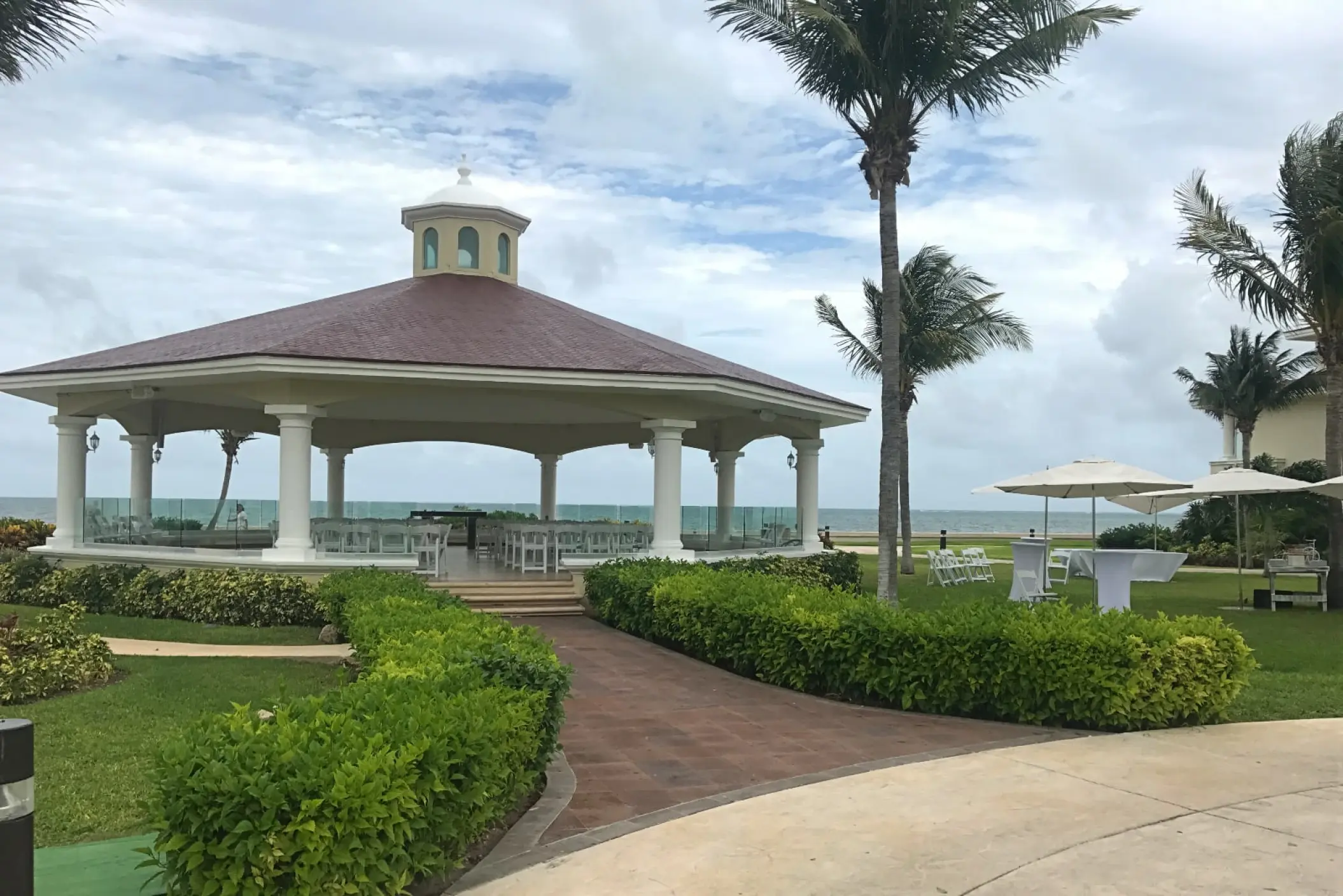 Oceanfront wedding gazebo with a brown roof and white pillars at Moon Palace Cancun