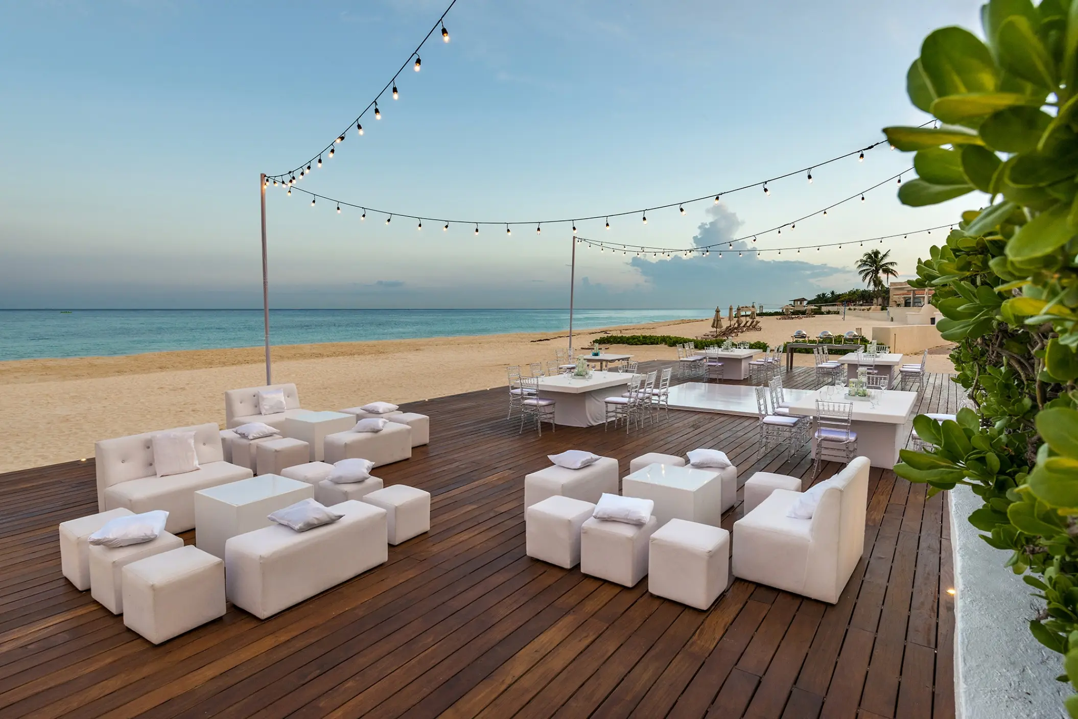 Outdoor wedding reception lounge with white furniture on a wooden deck at Moon Palace Cancun