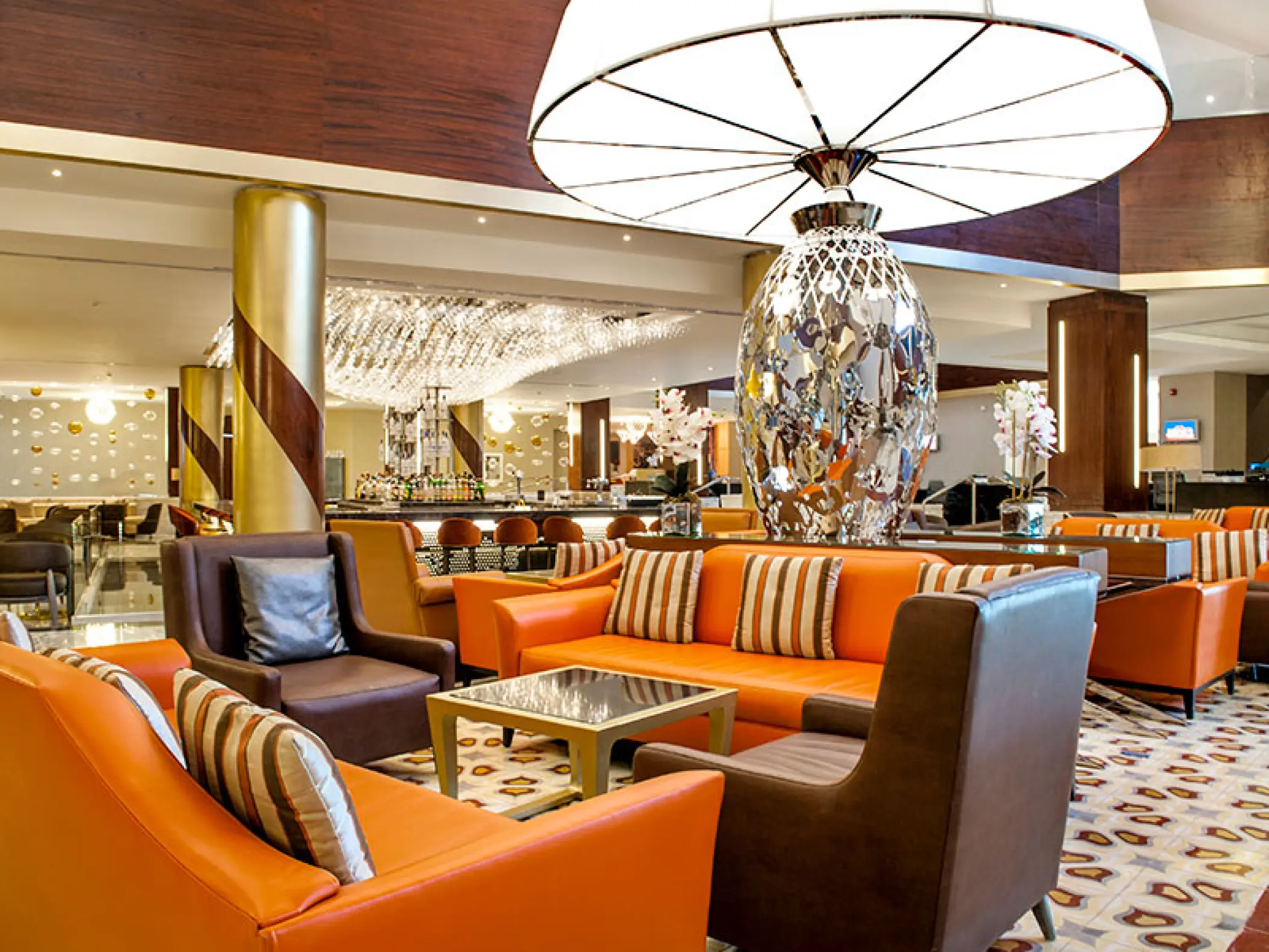 Modern lobby lounge with orange sofas and large decorative lamp at Moon Palace Cancun
