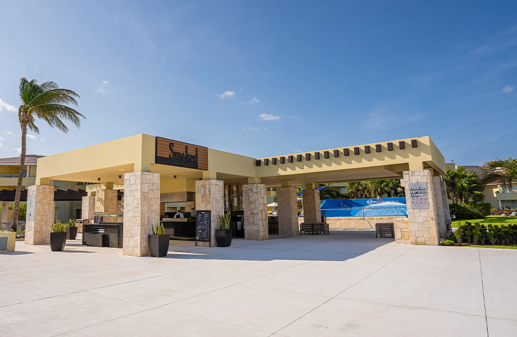 Outdoor restaurant with stone pillars under a blue sky at Moon Palace Cancun