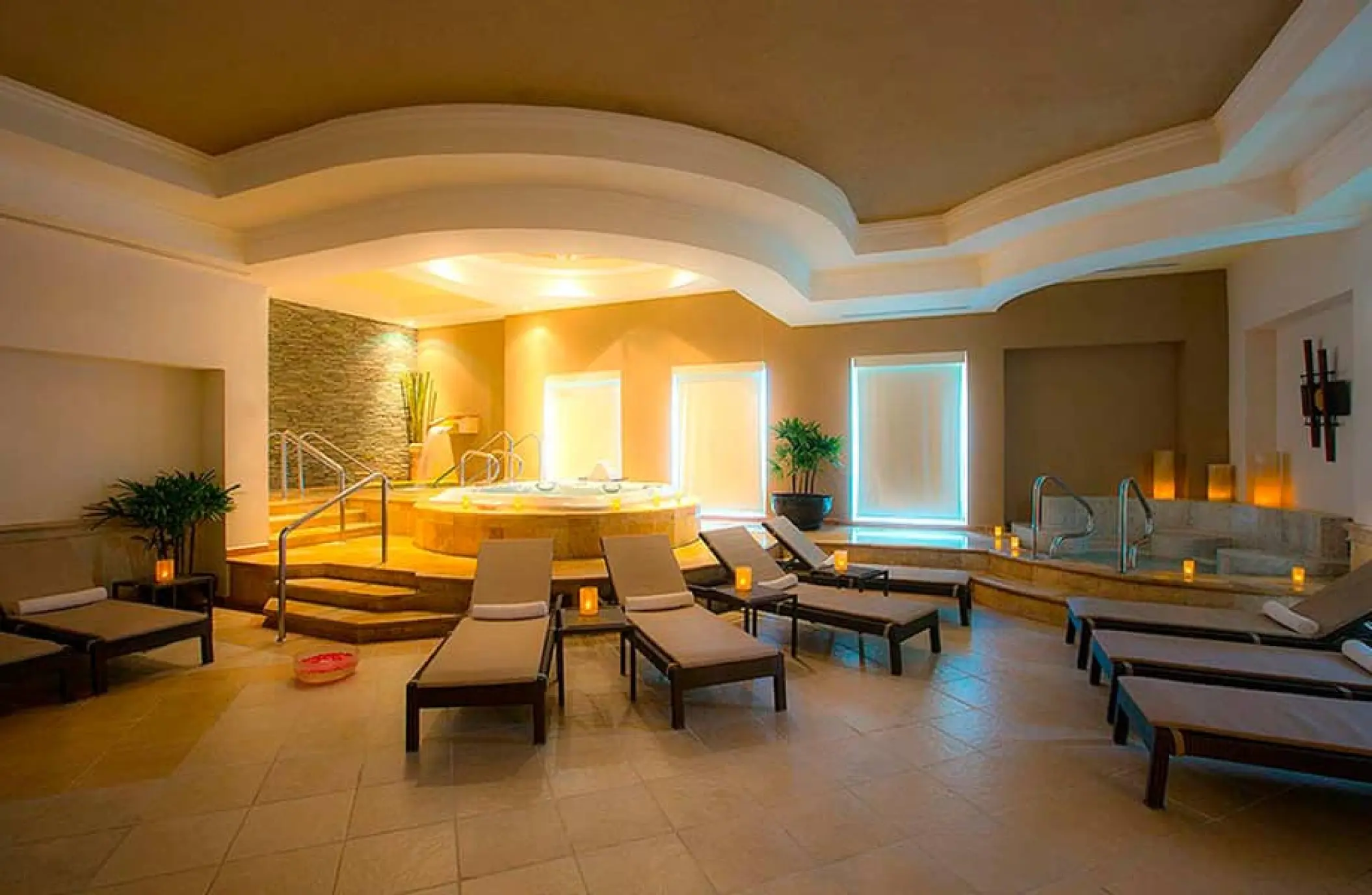 Indoor spa lounge with hydrotherapy pool and reclining loungers at Moon Palace Cancun