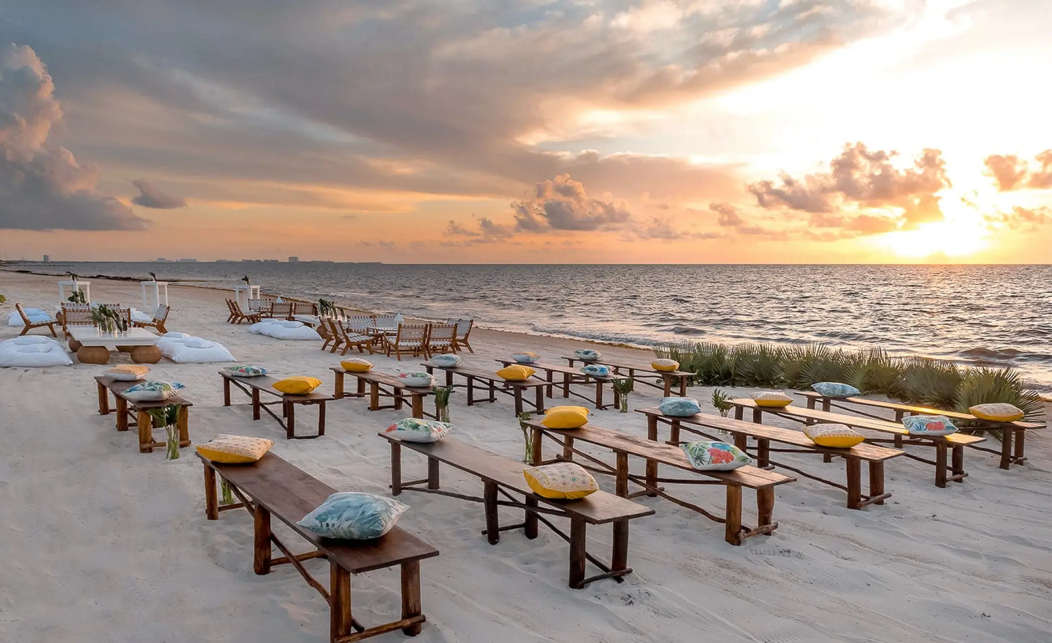 Beachfront wedding ceremony setup with wooden benches at Moon Palace Cancun
