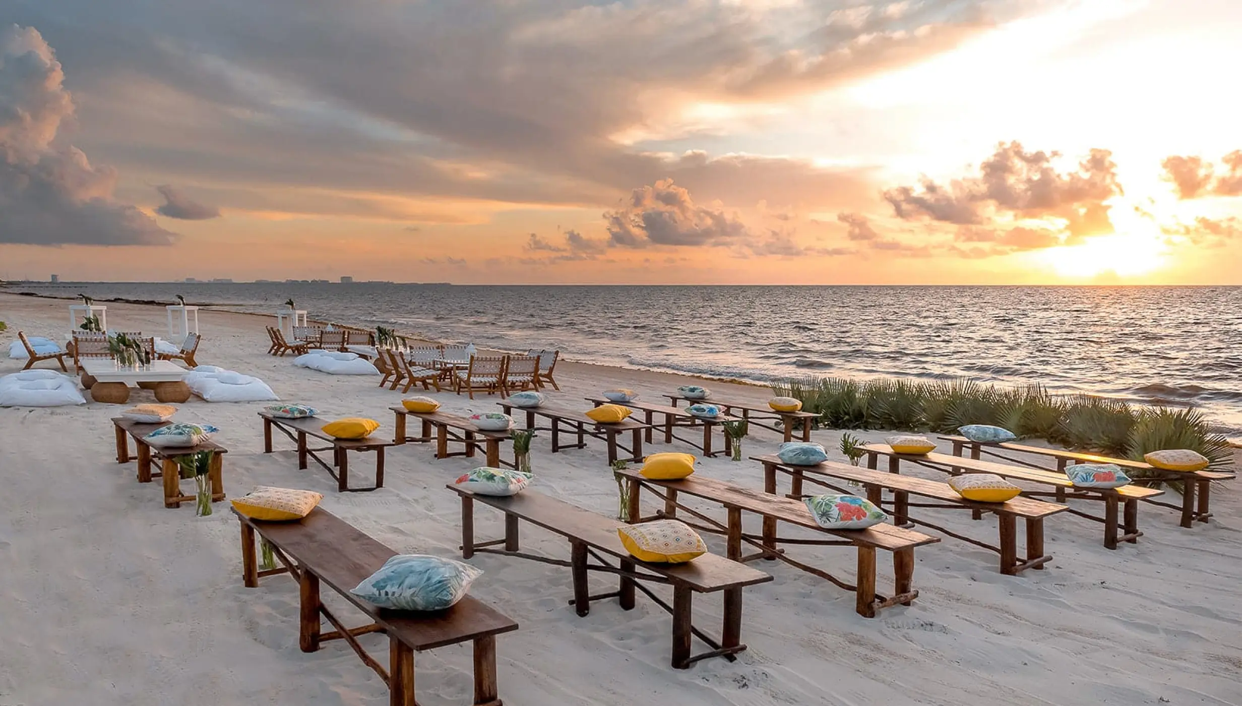 Beachfront wedding ceremony setup with wooden benches at Moon Palace Cancun