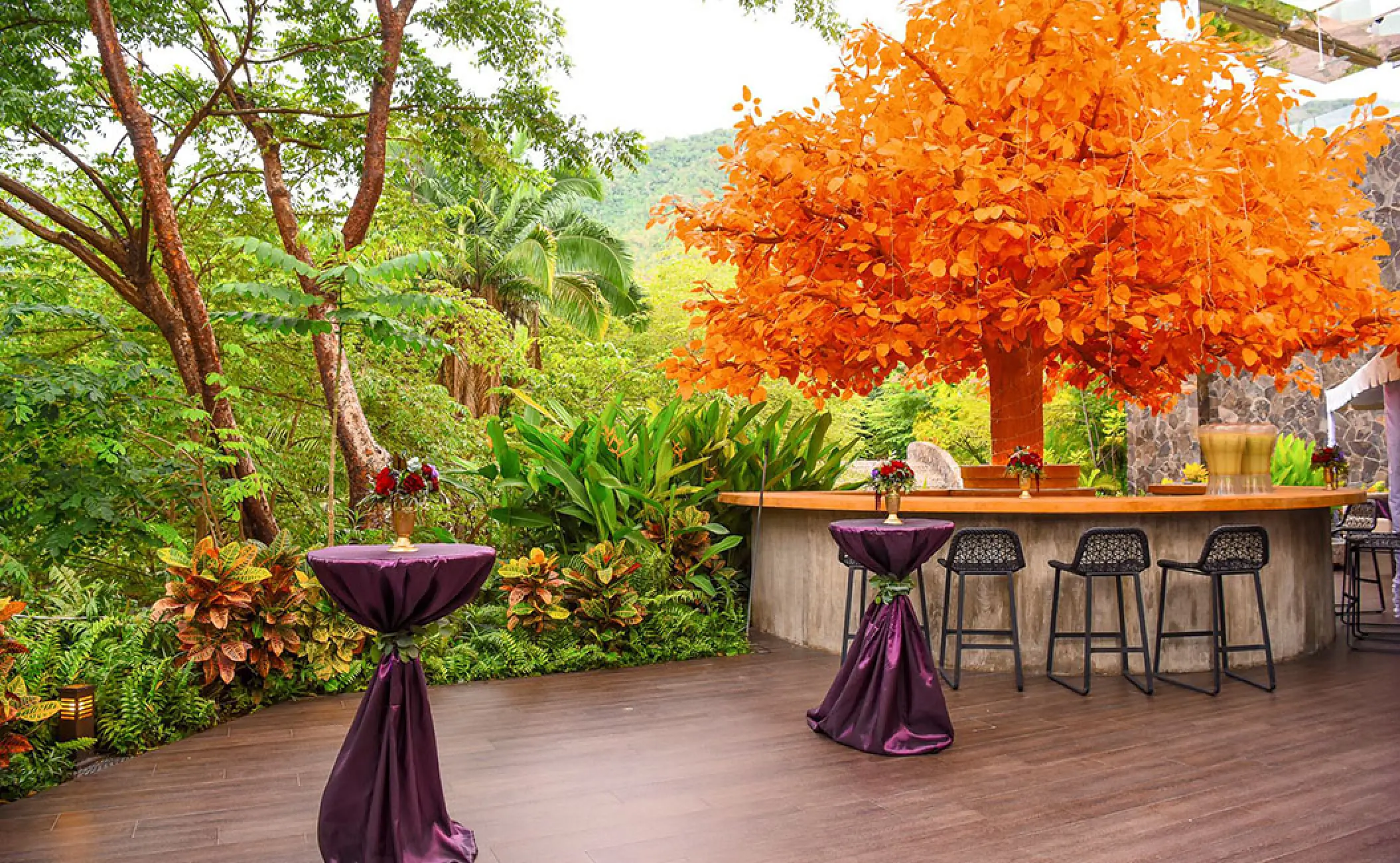 Outdoor cocktail hour at Garza Blanca Preserve, Puerto Vallarta featuring an orange tree and purple bistro tables