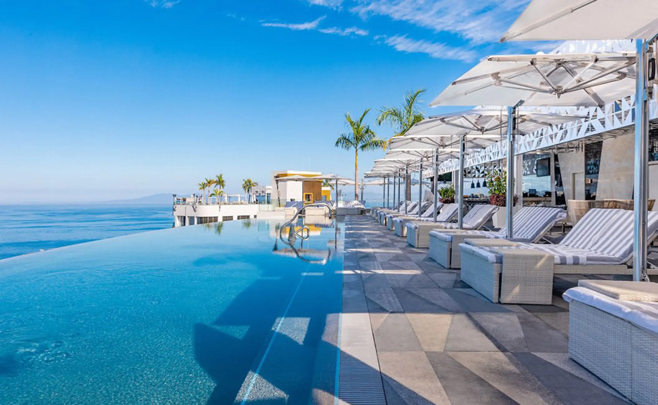 Rooftop infinity pool with lounge chairs at Hotel Mousai, Puerto Vallarta