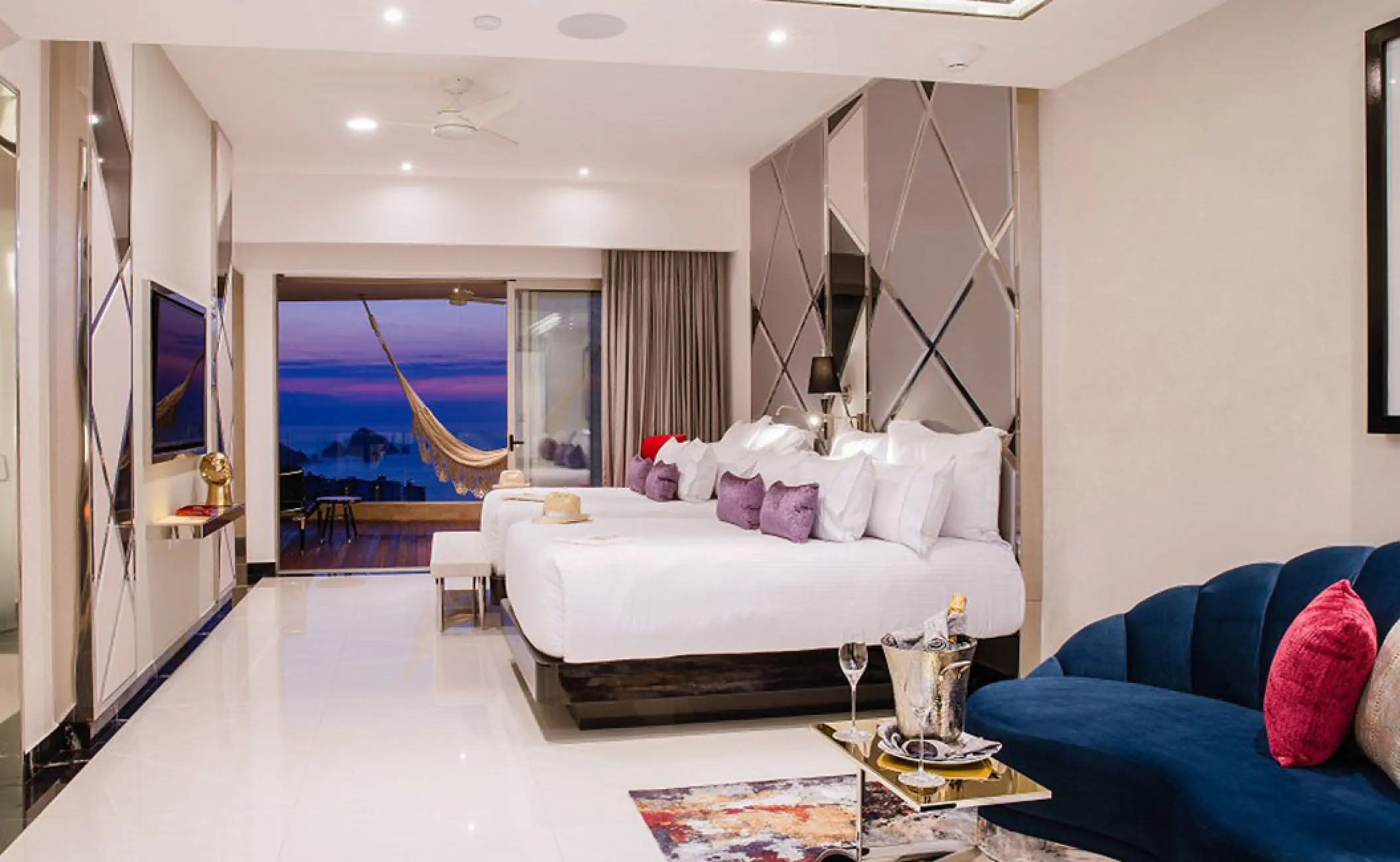 Hotel Mousai Puerto Vallarta suite with two beds, private terrace, and hammock overlooking the ocean at sunset