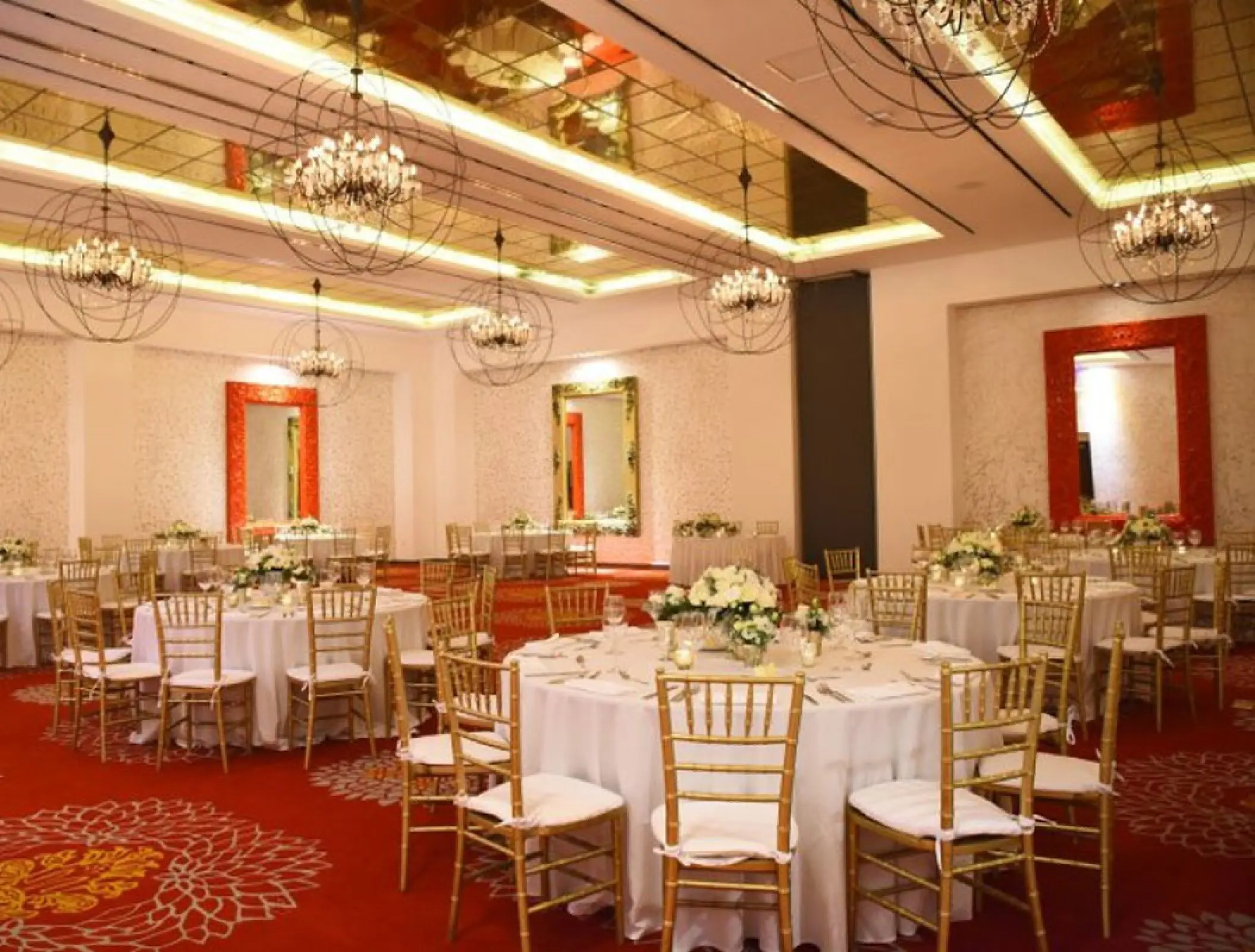 Indoor wedding reception with gold chairs and orb chandeliers at Hotel Mousai, Puerto Vallarta