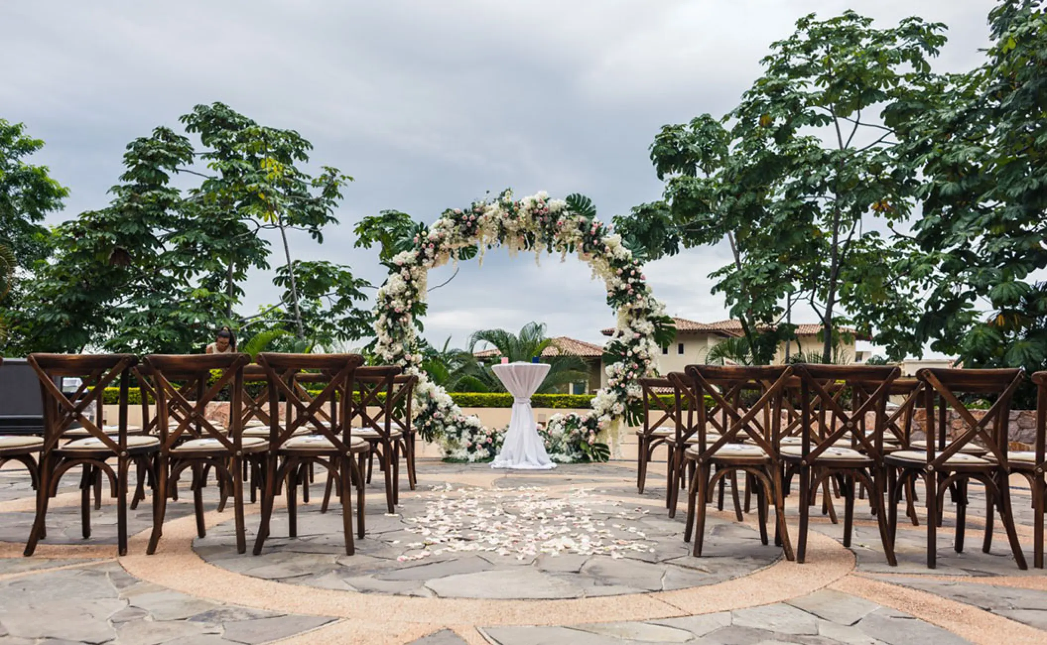 Outdoor wedding ceremony with circular floral arch and wooden cross-back chairs at Garza Blanca Puerto Vallarta