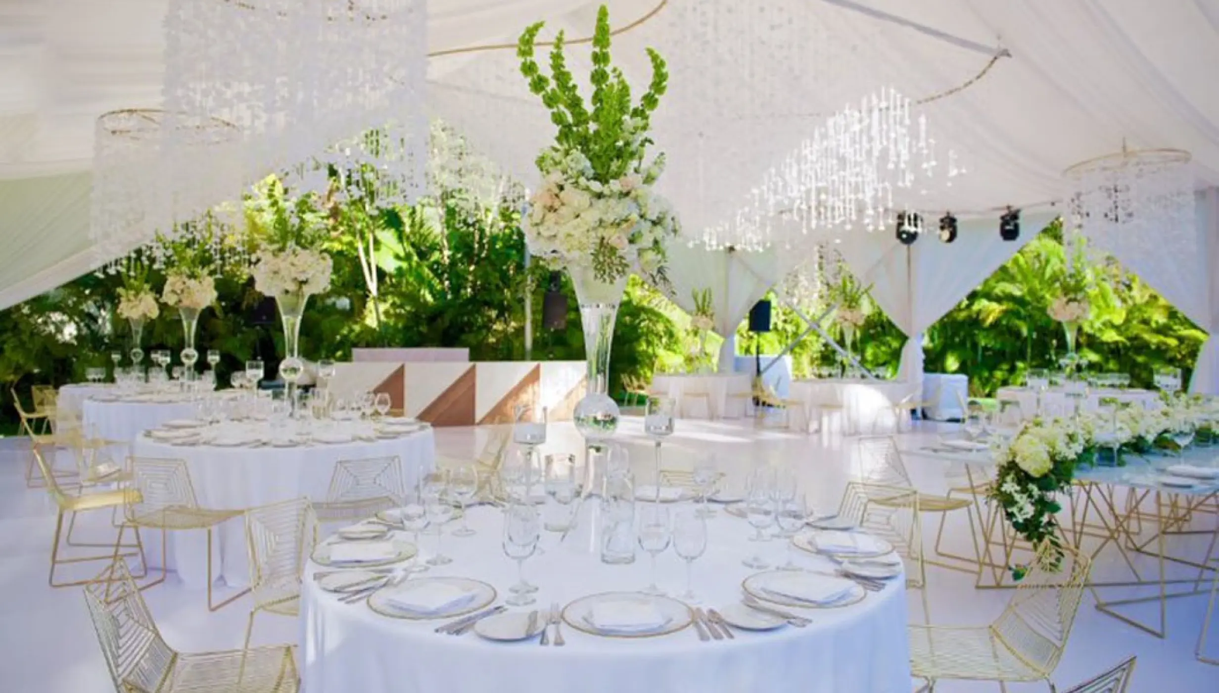 White outdoor wedding reception with floral centerpieces and chandeliers at Garza Blanca Puerto Vallarta