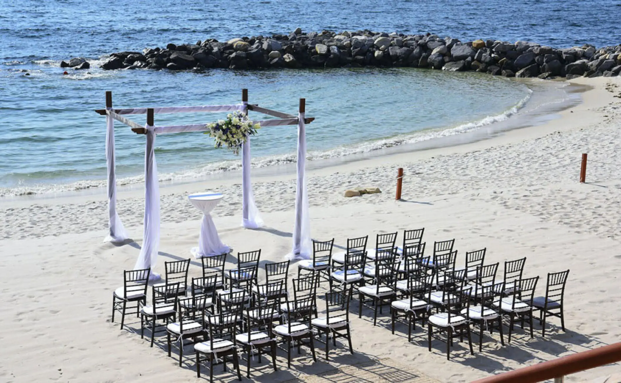 Beachfront wedding ceremony with dark wood chairs and white gazebo at Garza Blanca Preserve, Puerto Vallarta