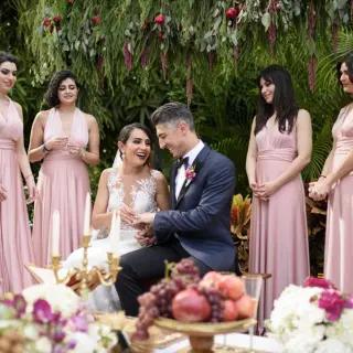 The groom placing a ring on the bride's finger surrounded by bridesmaids at Garza Blanca Preserve, Puerto Vallarta