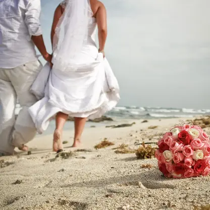 Bride and groom walking barefoot on the beach at Hilton Tulum