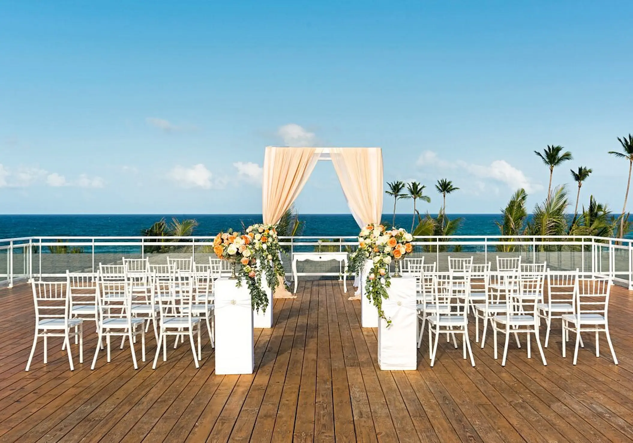 Rooftop wedding ceremony with white chairs and floral arch at Nickelodeon Punta Cana