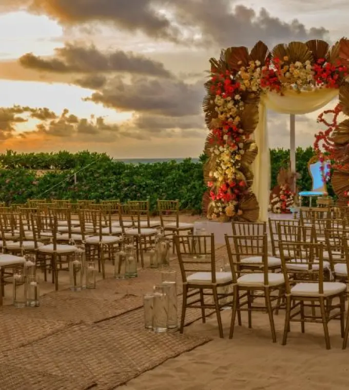 Beachfront wedding ceremony setup with floral arch at Nickelodeon Riviera Maya