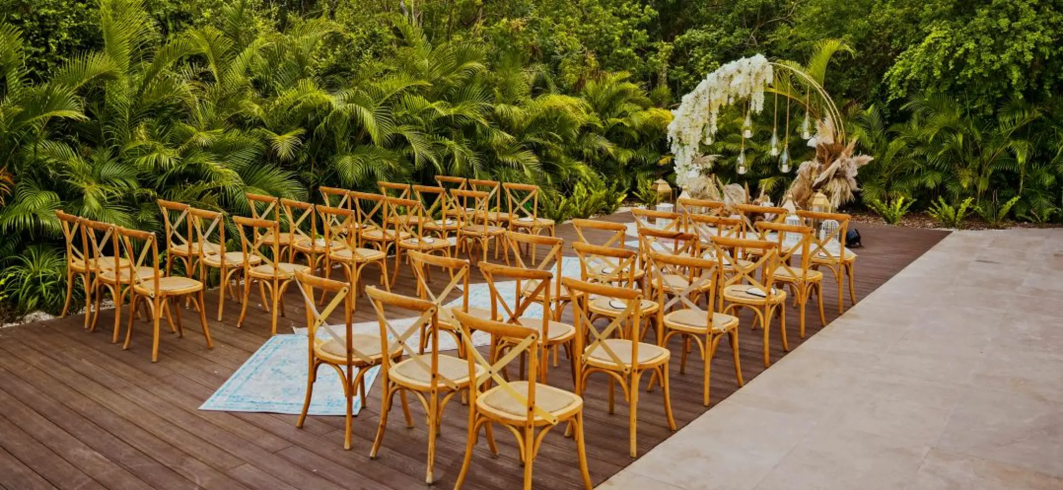Garden wedding ceremony setup with wooden cross-back chairs at Nickelodeon Riviera Maya